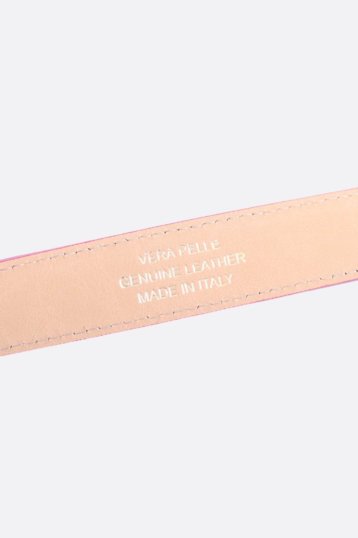 Zoom sur la texture grainée de la ceinture fuchsia en cuir, ajoutant une note d'élégance à une tenue moderne.