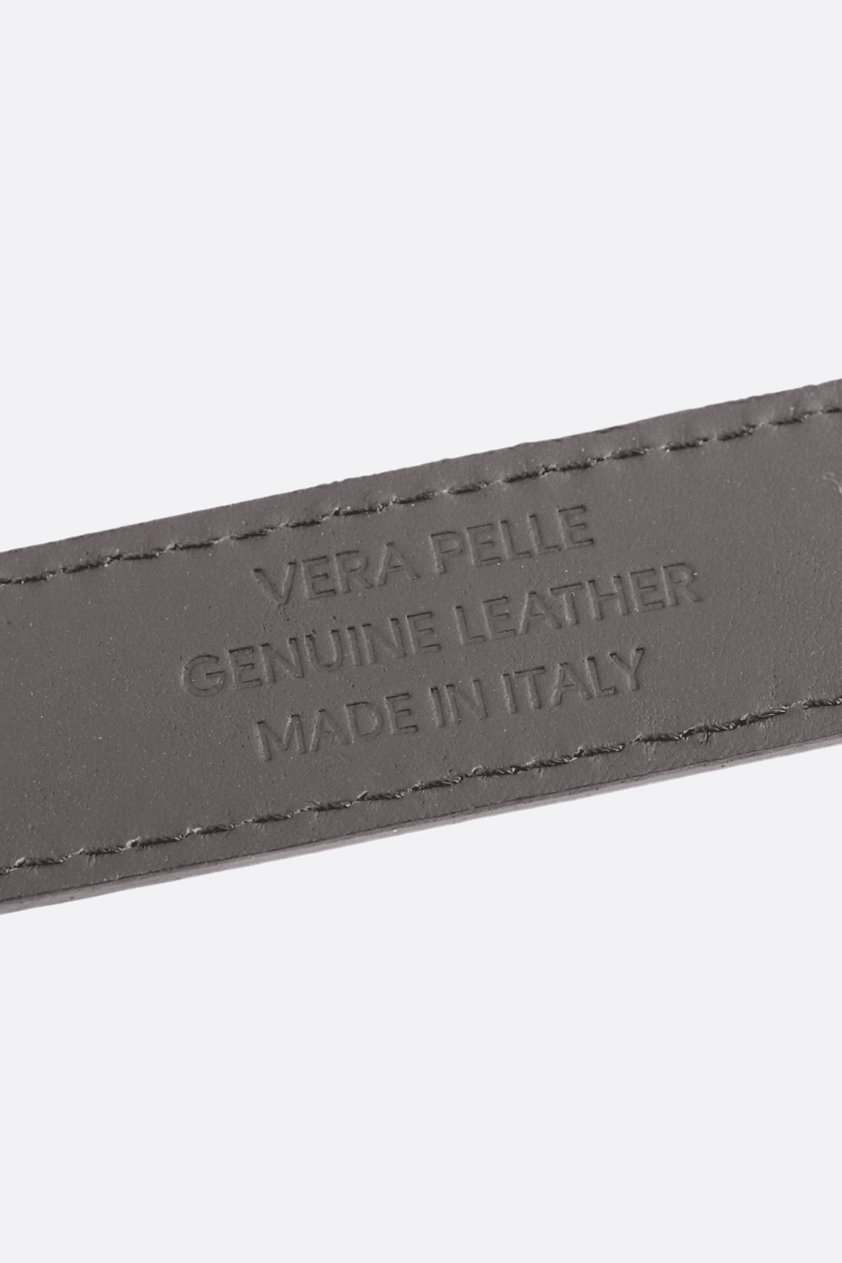 Détail sur la texture de la ceinture en cuir noir, un accessoire italien chic pour une allure moderne et élégante.
