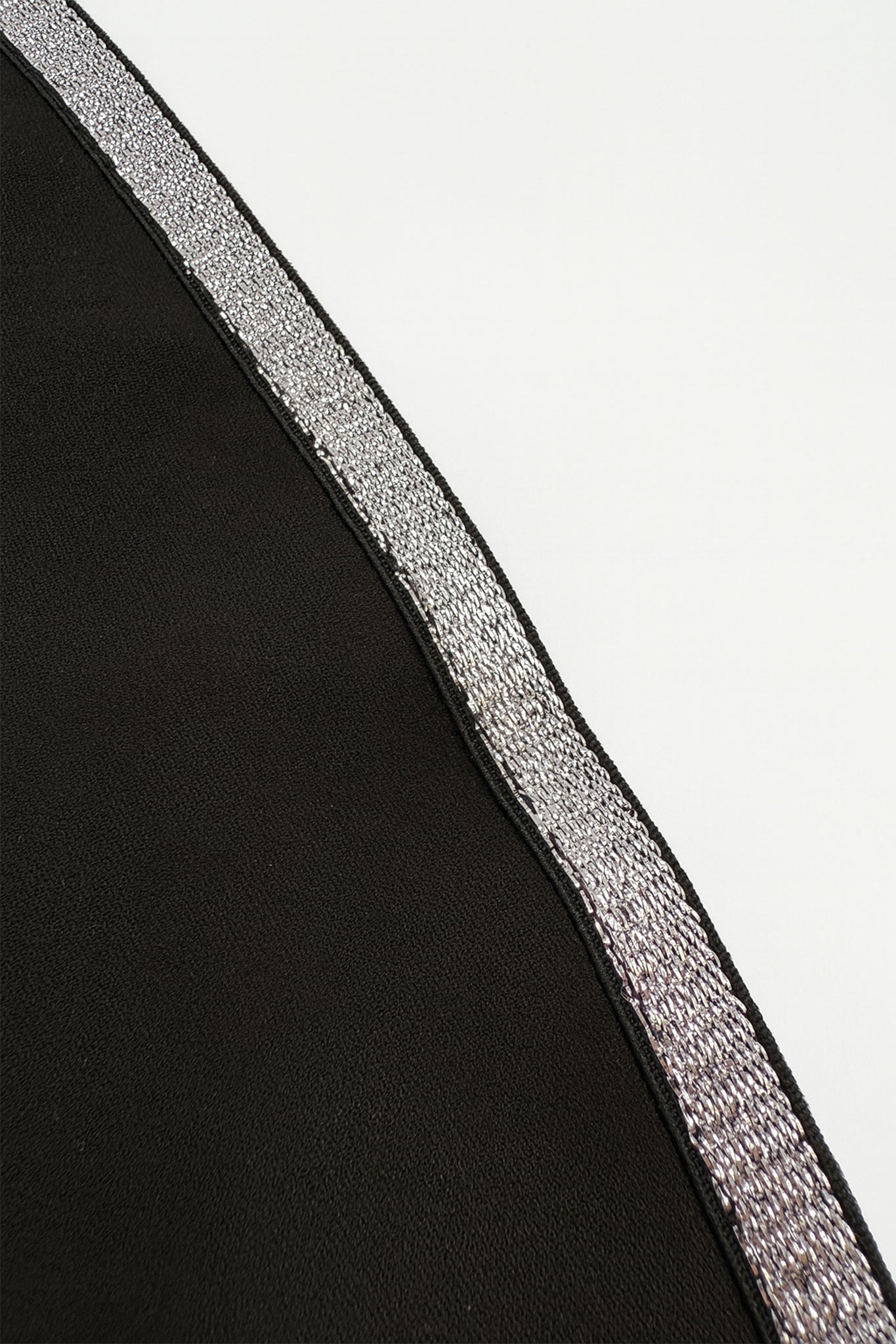 Détail captivant de la combinaison noire asymétrique, révélant une texture luxueuse et un design chic pour soirées élégantes.