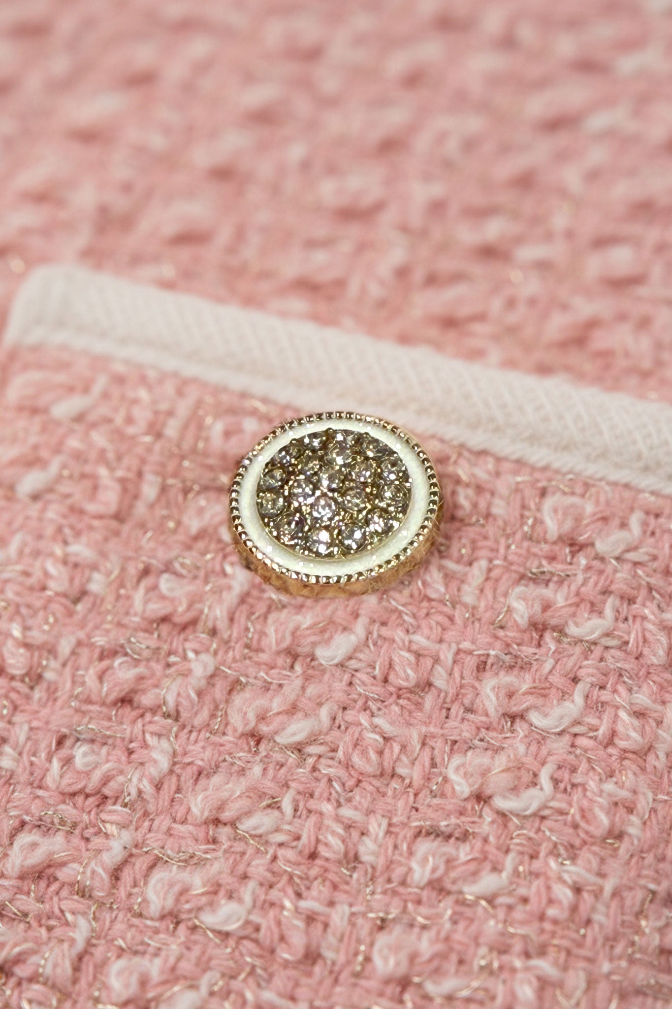 Finesse du tissu en tweed rose sur la jupe courte et la veste à poches, un choix délicat pour des occasions élégantes.