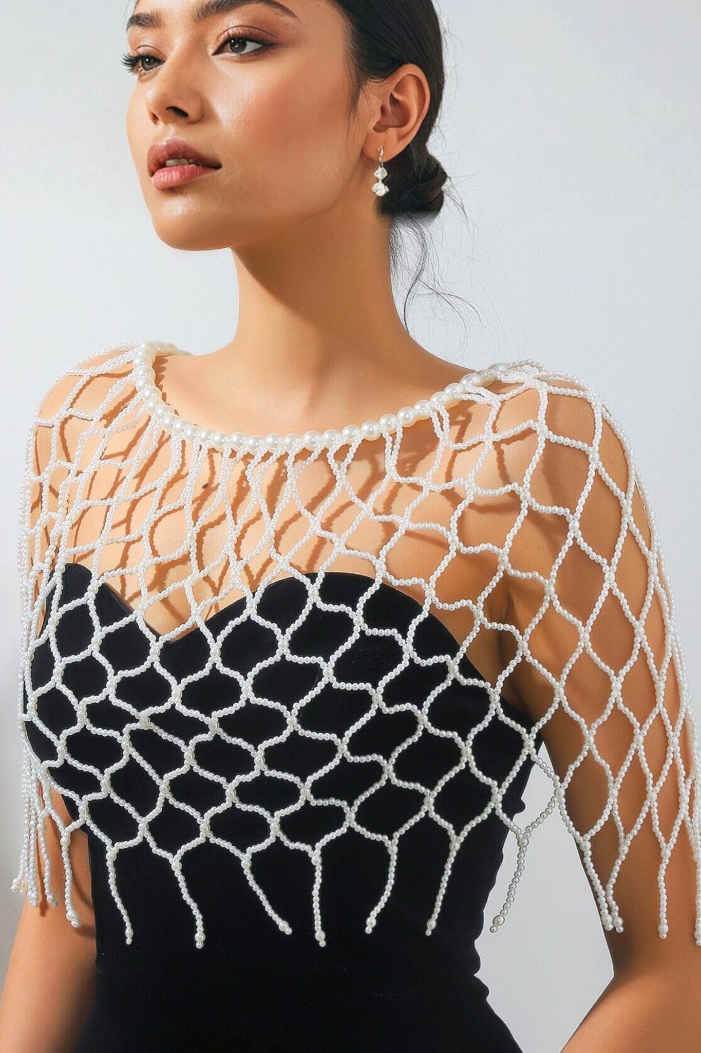 Détail artistique de l'étole en perles ivoire, accessoire moderne pour une silhouette chic lors d'événements nocturnes.