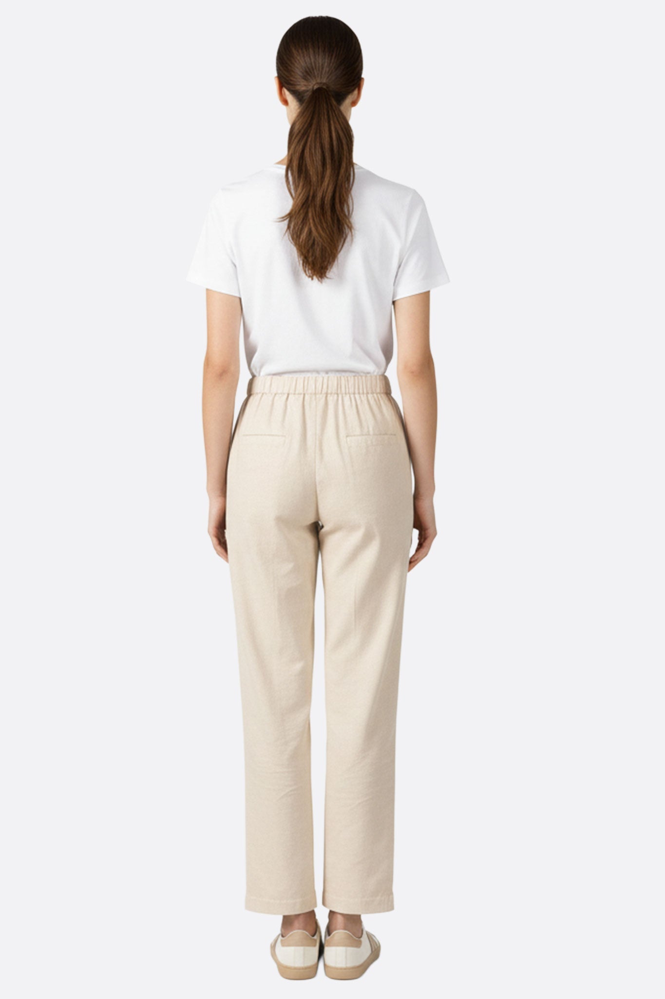 Détail du dos du pantalon beige à taille haute élastique, soulignant la souplesse du tissu et le confort pour une tenue chic.