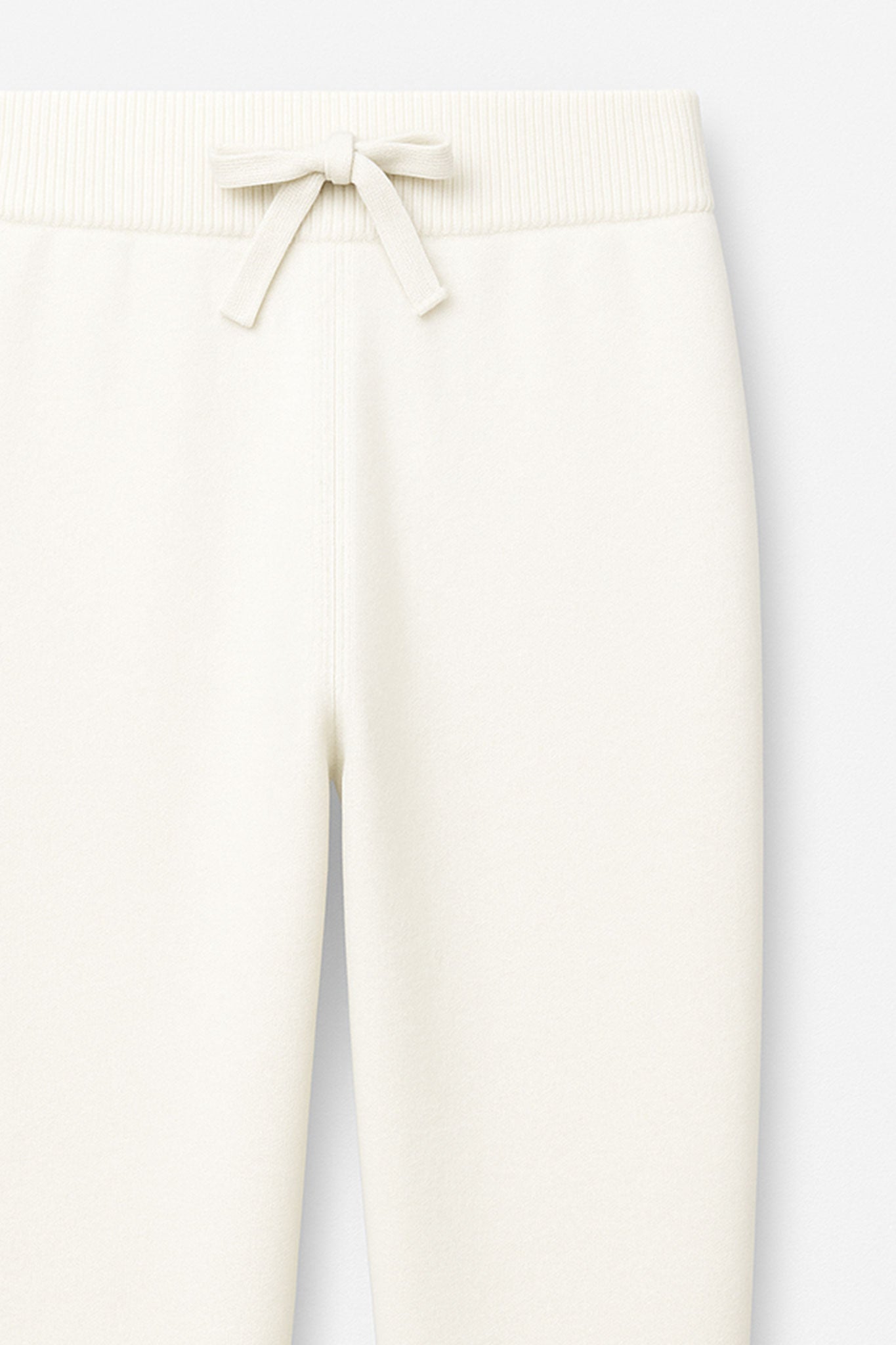Détail du pantalon fluide en laine blanche, taille élastique, parfait pour une tenue raffinée au bureau ou lors...