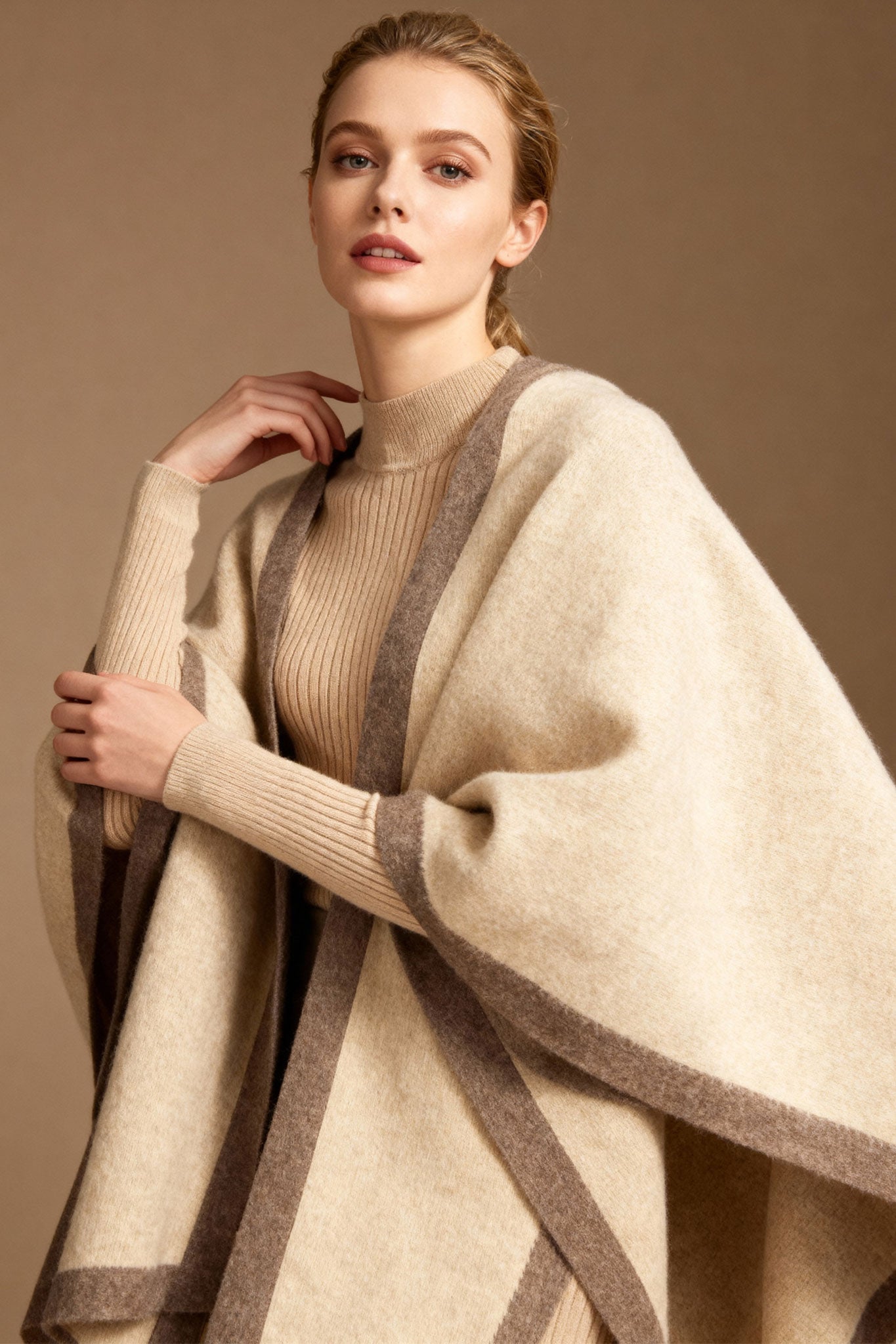 Détail du poncho en cachemire beige avec bandes taupe, un accessoire raffiné pour apporter chaleur et élégance au quotidien.