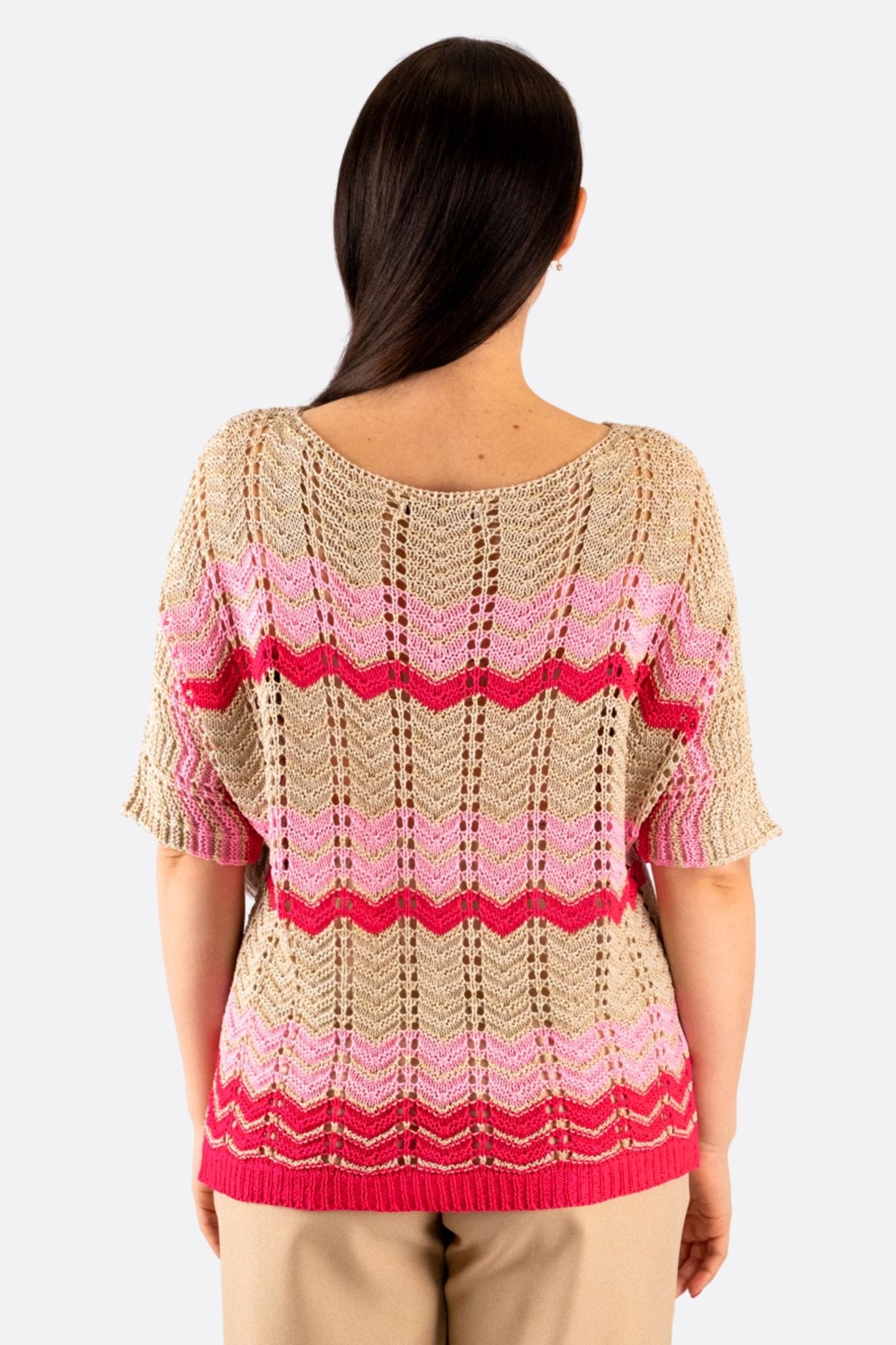 Texture délicate d'un pull beige ajouré avec motifs chevrons roses, parfait pour une allure moderne et élégante.