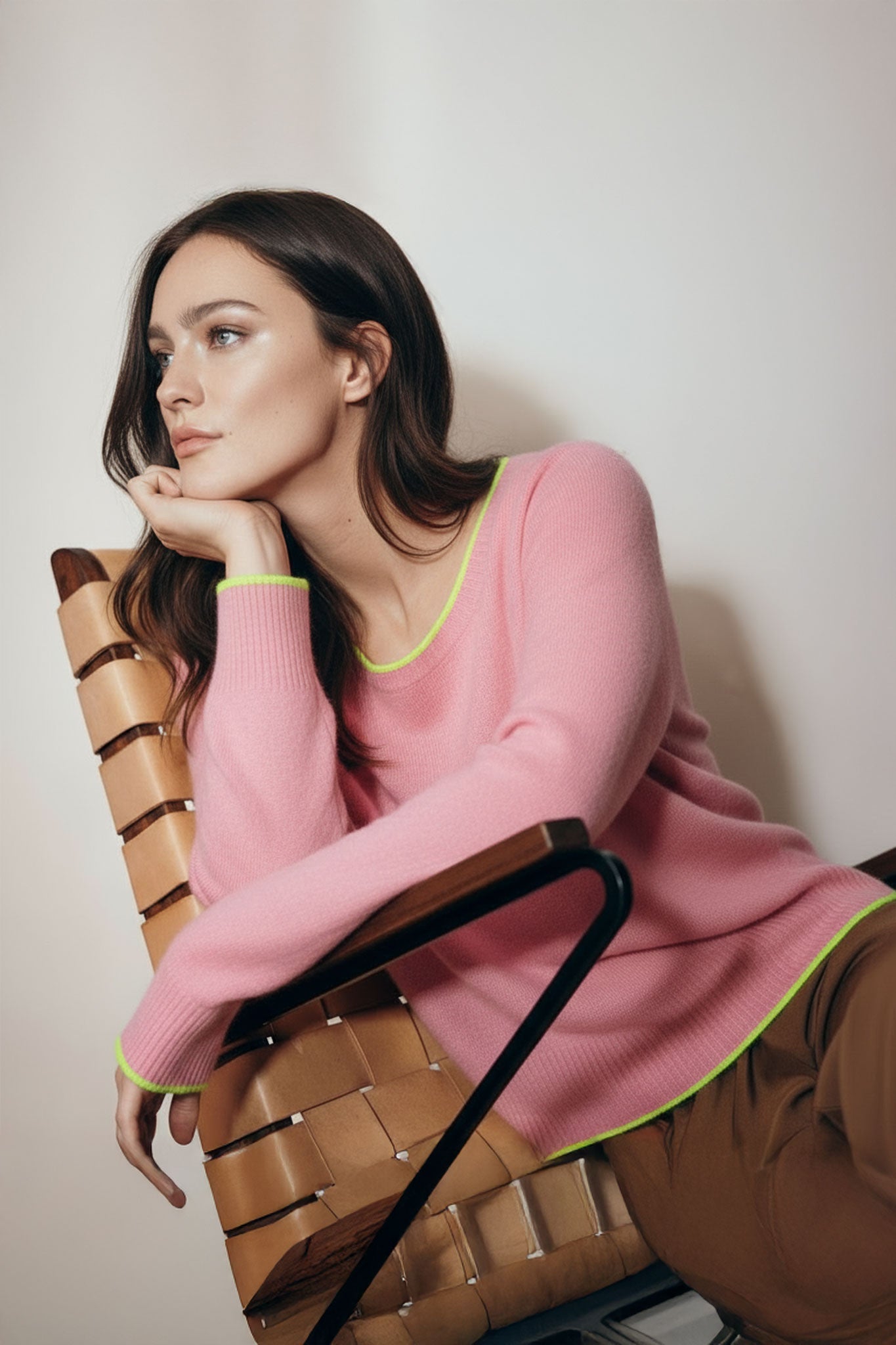 Détail élégant d'un pull rose en laine mérinos et cachemire, mettant en avant les finitions jaunes fluo pour un style...