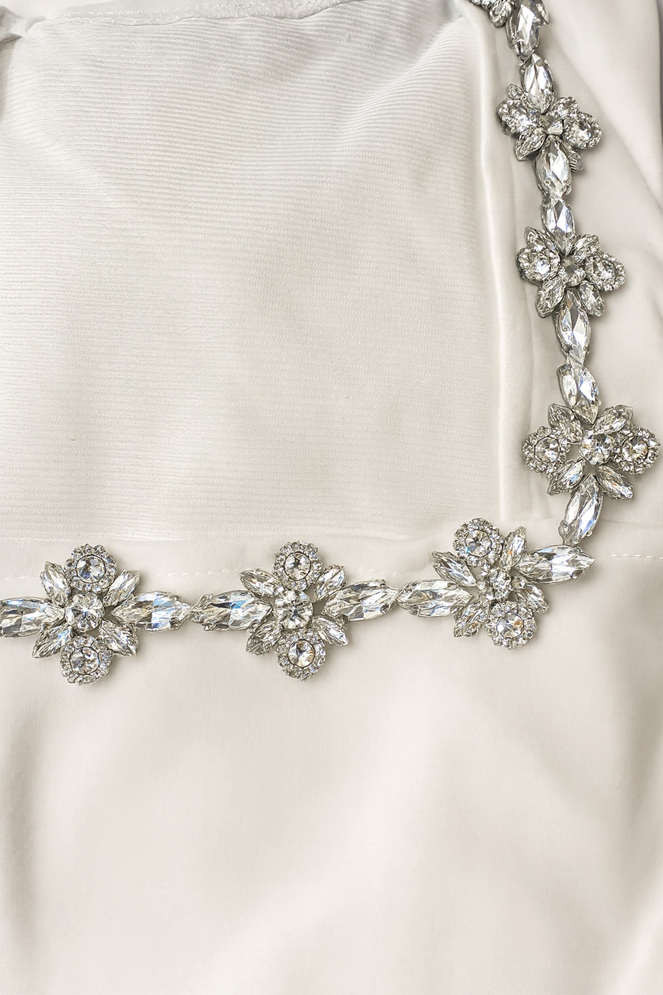 Détails de la robe courte blanche en crêpe, mettant en valeur les scintillements des bijoux pour une allure chic.