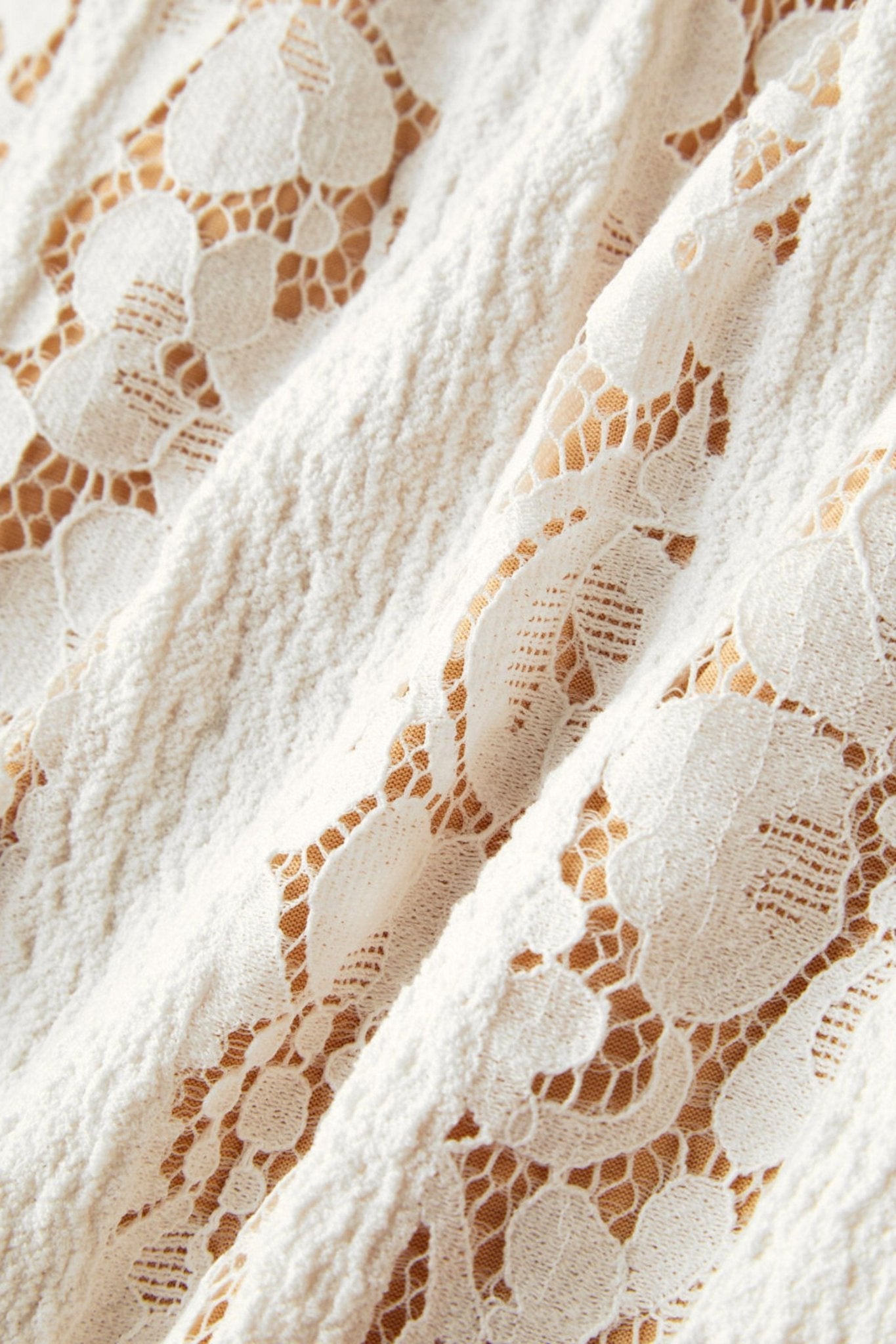 Détail raffiné de la robe en dentelle blanche, révélant la texture délicate et les épaules dénudées pour une touche élégante.