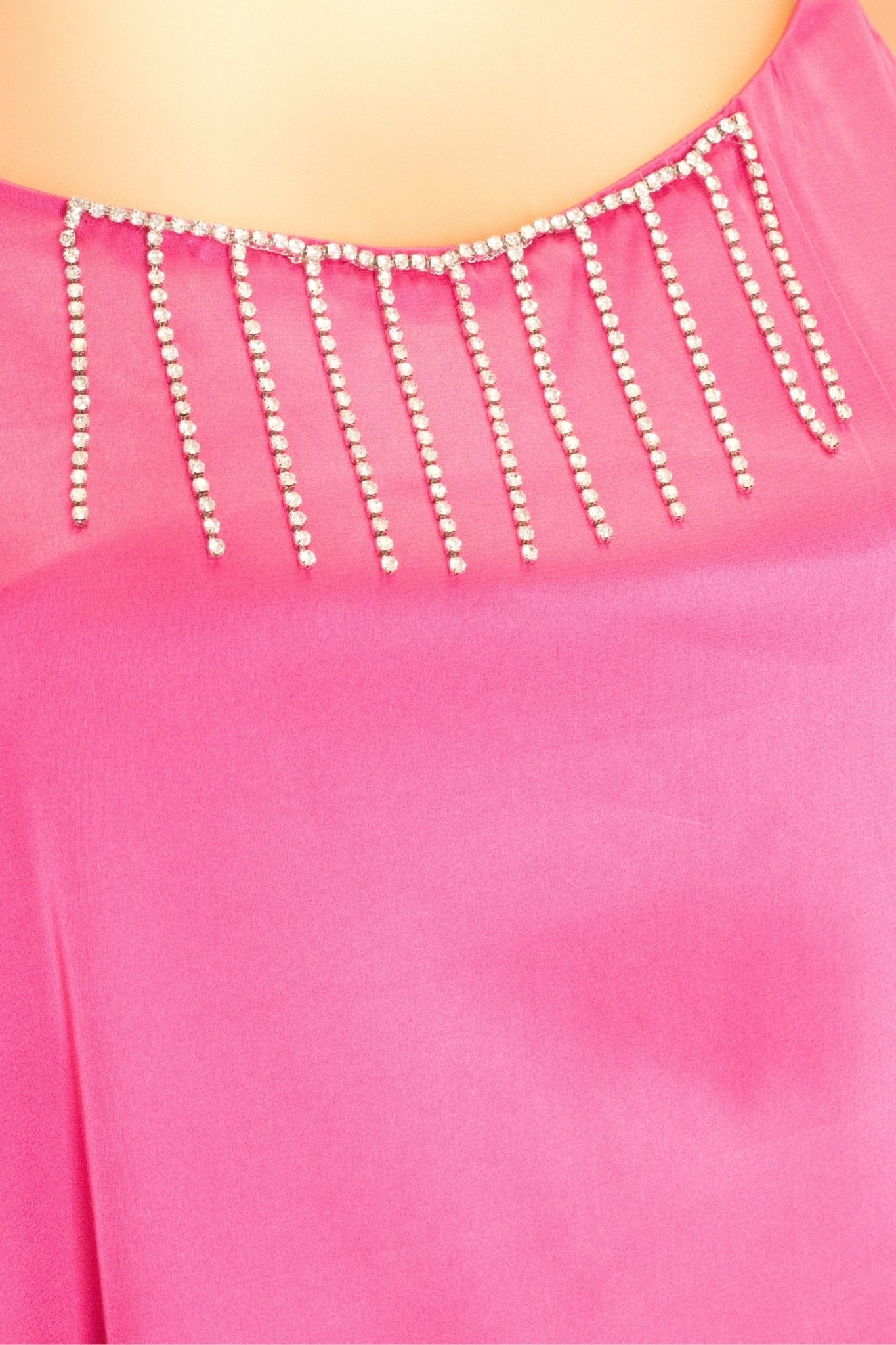 Détail de la robe fuchsia en satin, soulignée par des chaînettes de strass argentés, idéale pour des occasions raffinées.