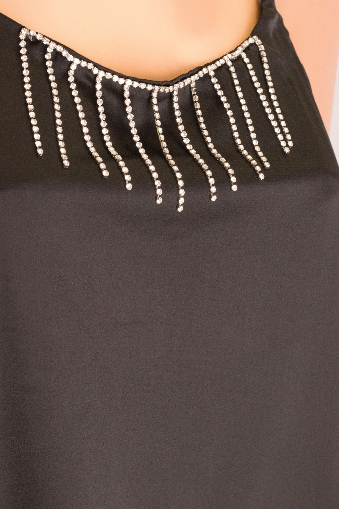 Détail des chaînettes en strass argentés sur la robe satinée noire, ajoutant une touche d'éclat pour une soirée raffinée.