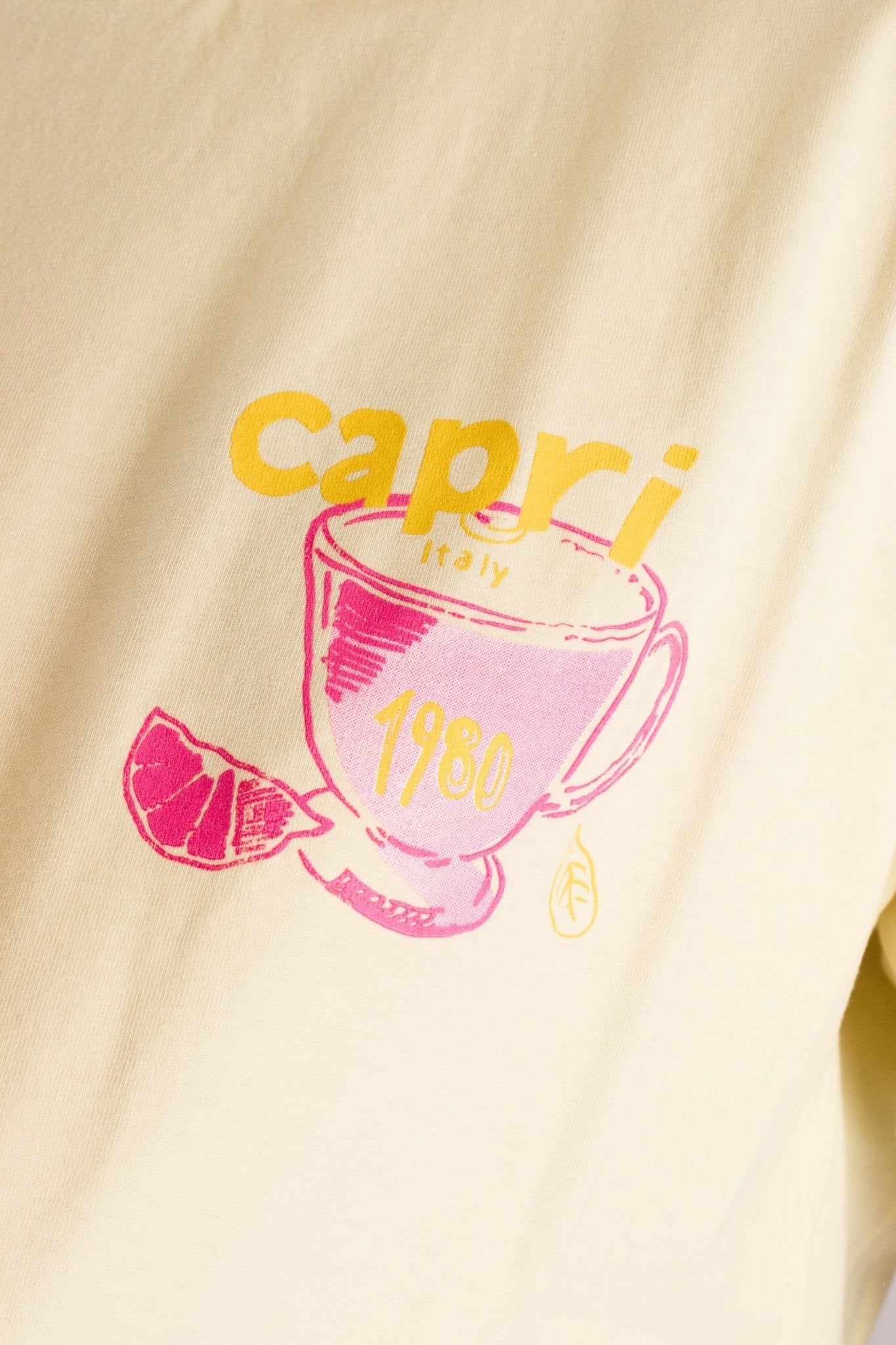 Détail du t-shirt ample jaune pastel, mettant en avant son imprimé Capri, parfait pour une allure chic au quotidien.