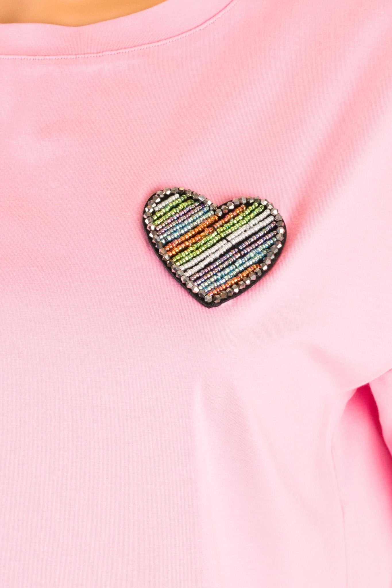 Détail du dos d'un t-shirt rose à manches courtes avec une charmante broderie en cœur, parfait pour les journées...