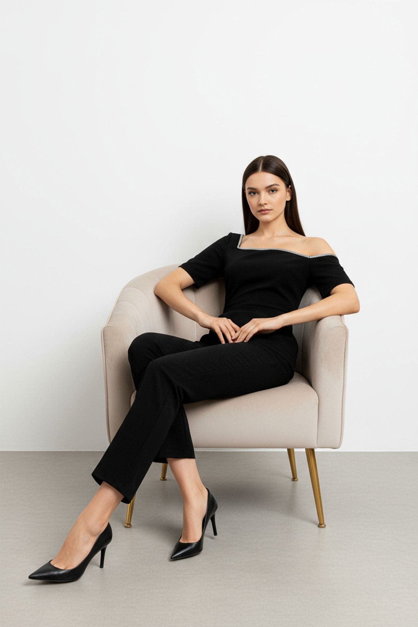 Dettaglio alternativo della tuta nera chic, che sottolinea la sua eleganza asimmetrica e il tessuto leggero dalla caduta fluida