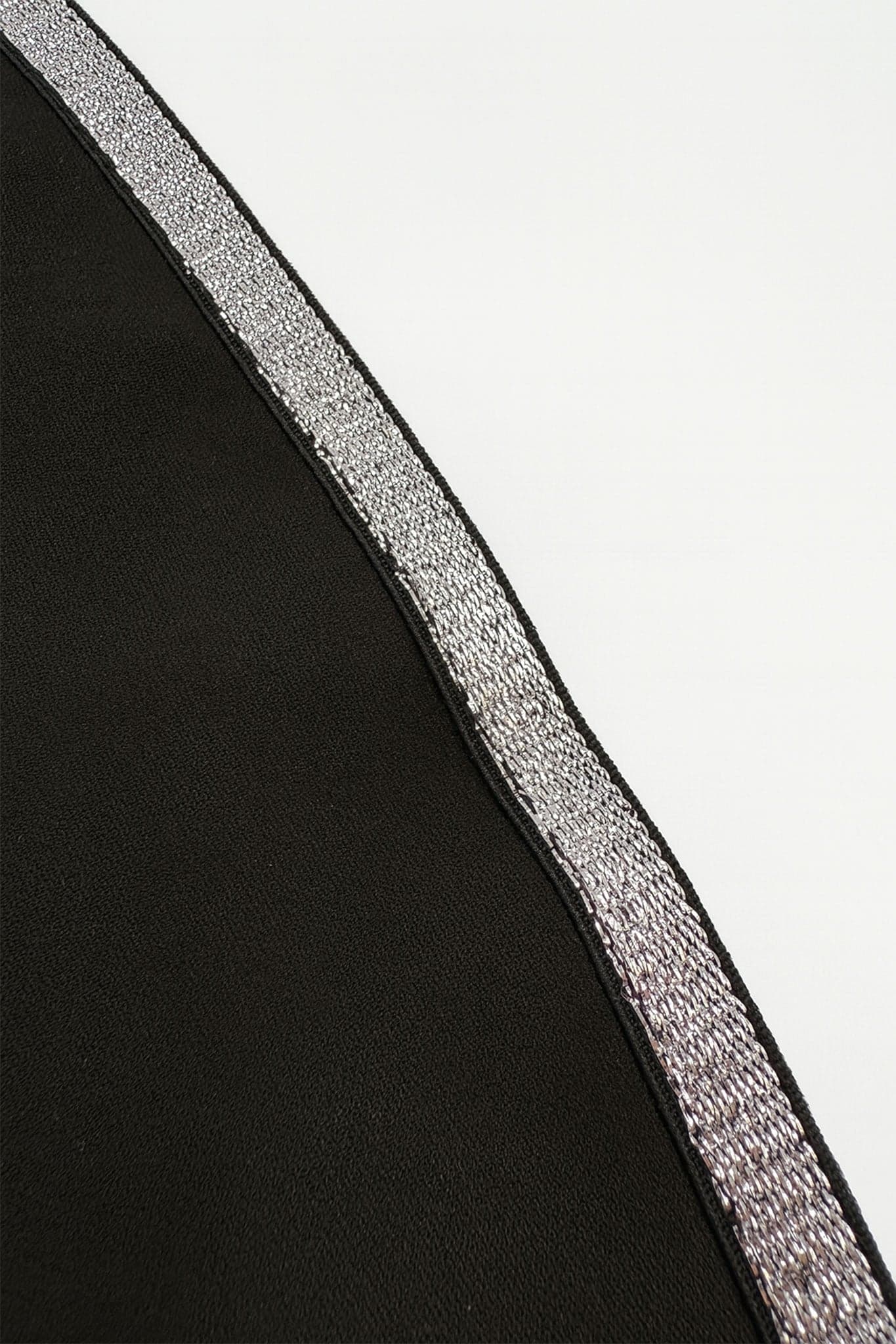 Dettaglio accattivante della tuta nera asimmetrica, che rivela una texture lussuosa e un design chic per serate eleganti
