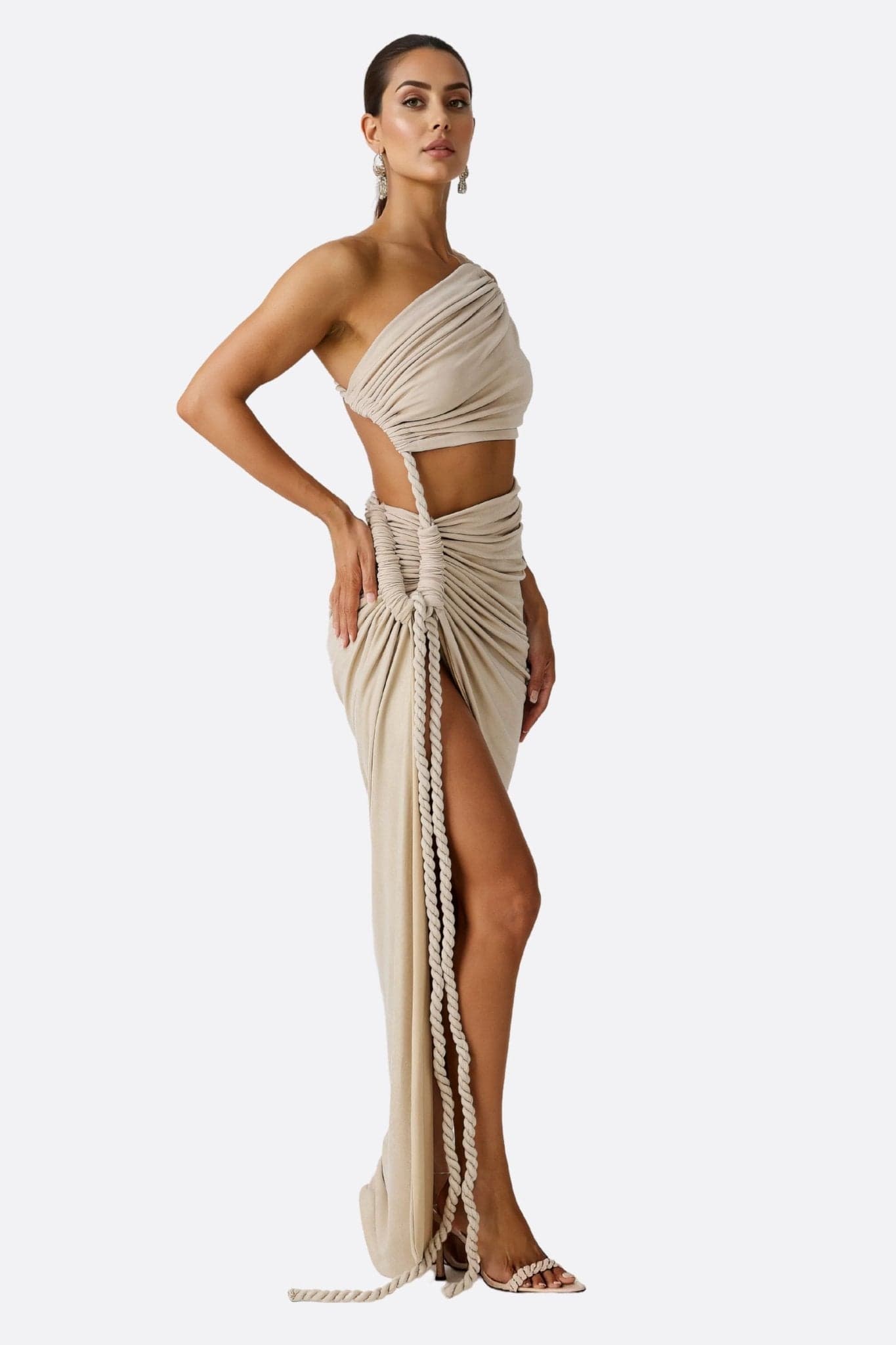 Elegantes Detail des drapierten beigen Beachwear-Sets, das seinen asymmetrischen Schnitt und fließenden Stoff hervorhebt.