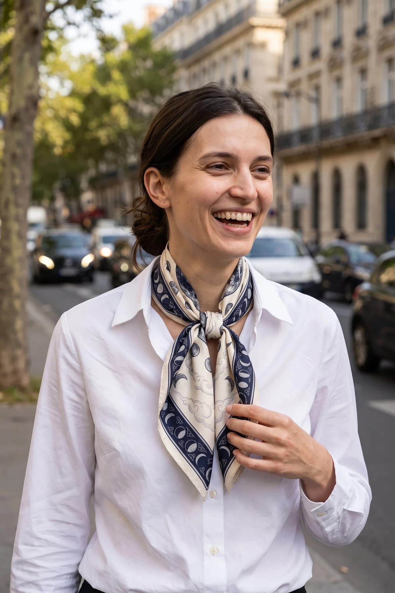 Frau trägt den Seidenschal Phases de la lune gebunden auf einer Straße in Paris