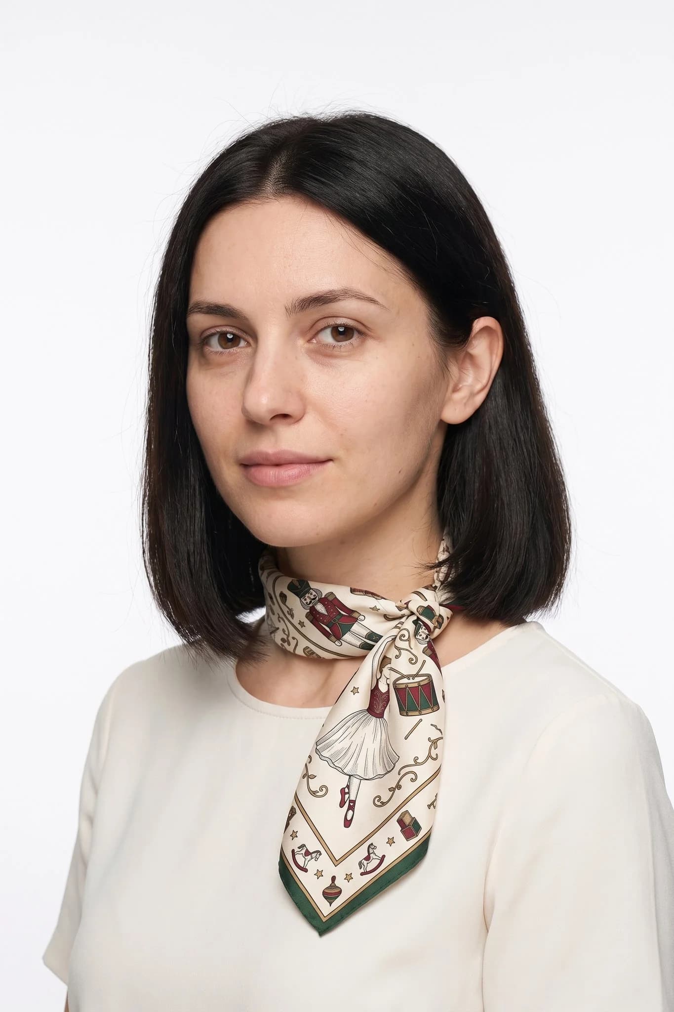 Small silk scarf 50 Casse-noisette worn tied around the neck as a small scarf by a woman, studio view