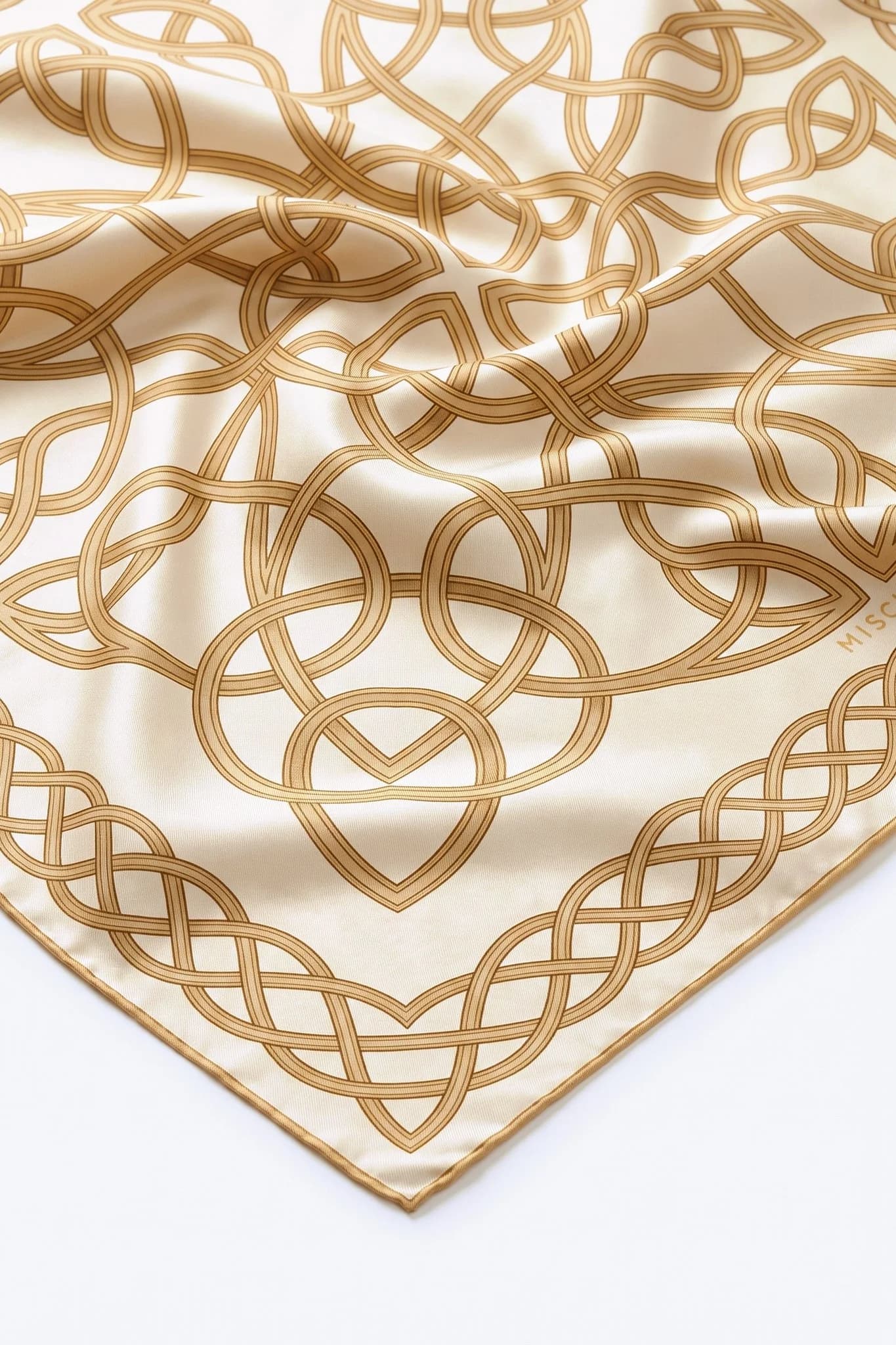 Close-up on the folds of the silk scarf Entrelacs d'or, silk twill and hand-rolled hem