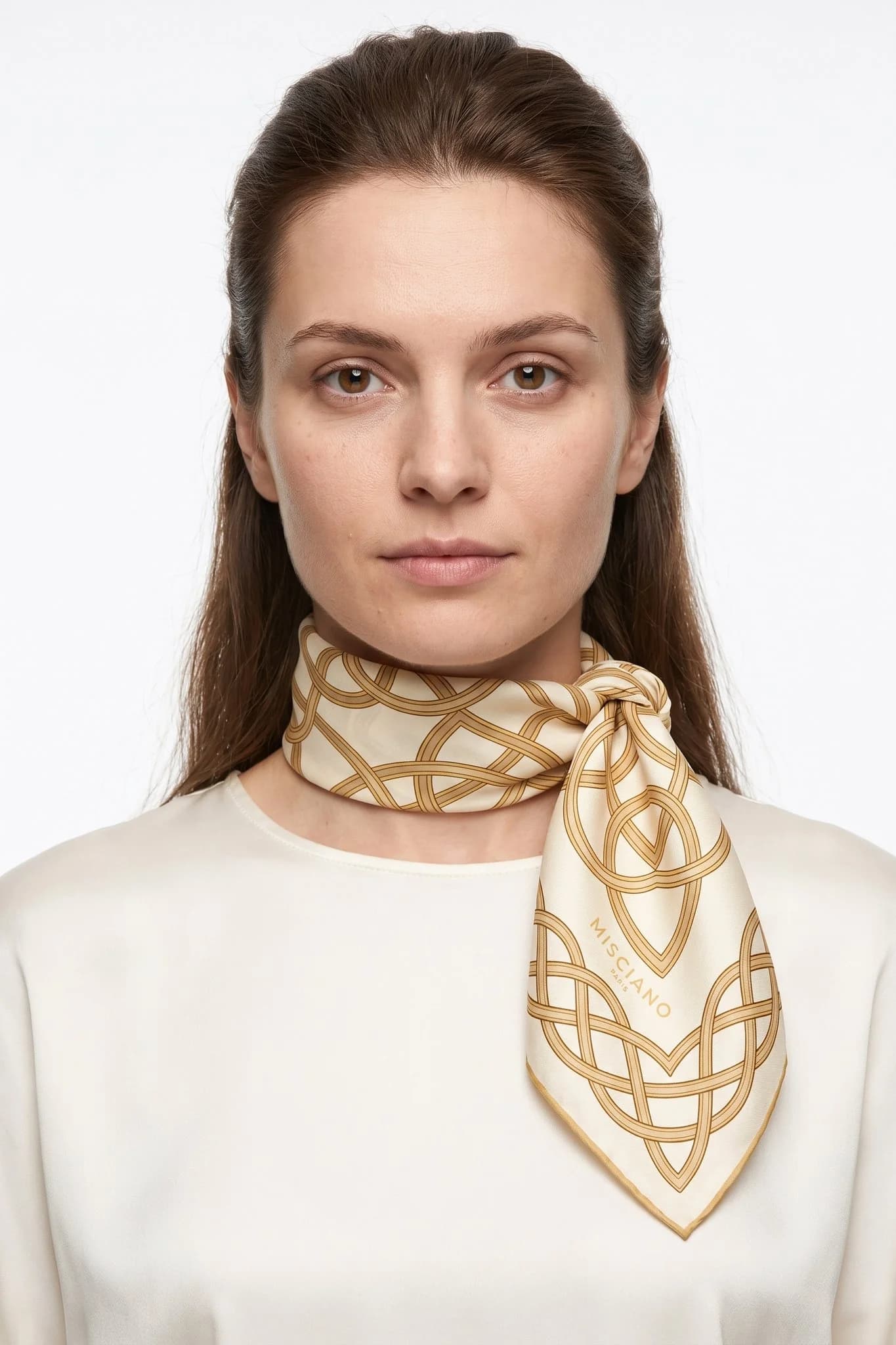 Small silk scarf 50 Entrelacs d'or worn tied around the neck as a small scarf by a woman, studio view