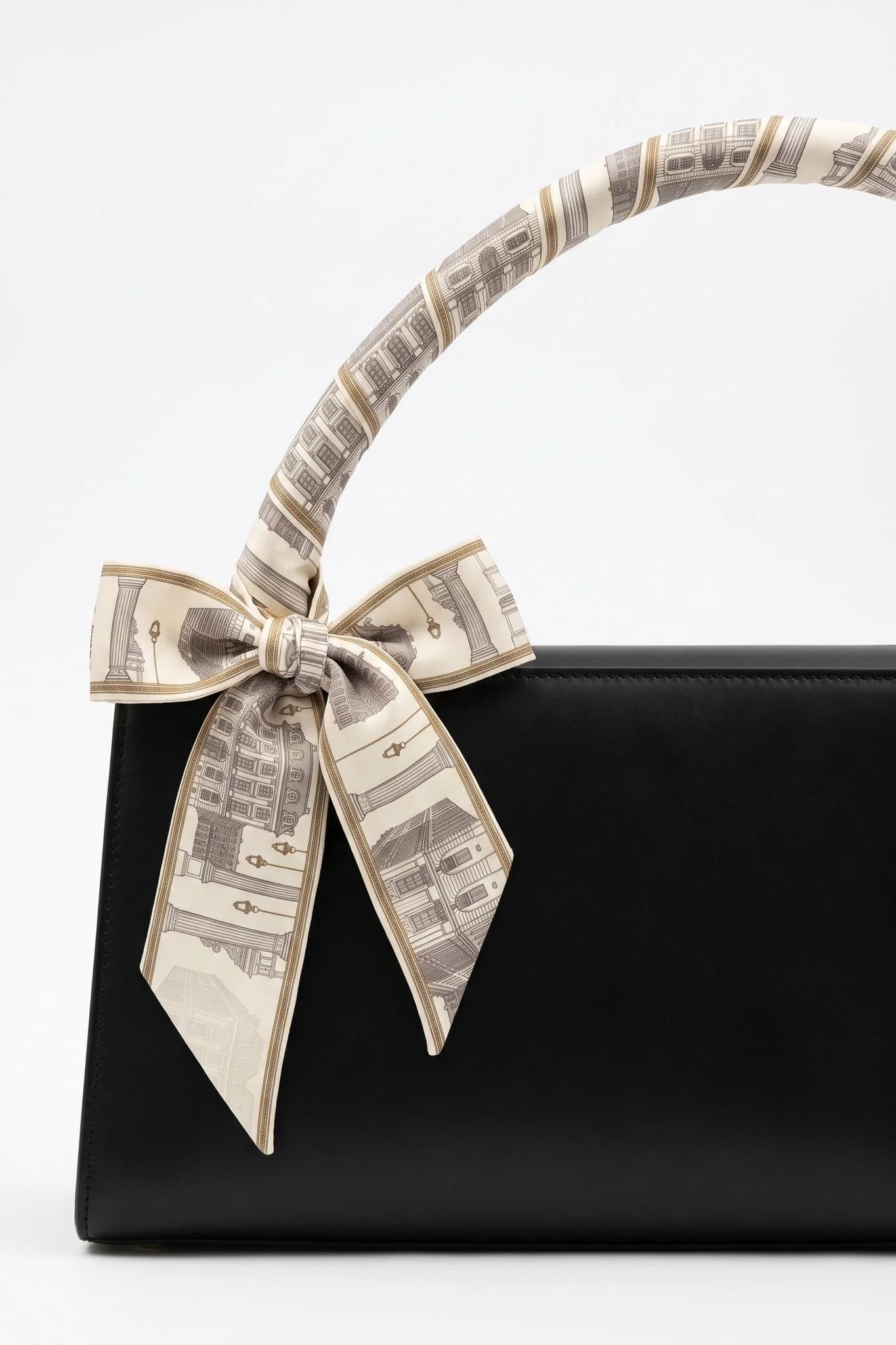 Twilly Place Vendôme arrotolato e annodato attorno al manico di una borsa in pelle nera