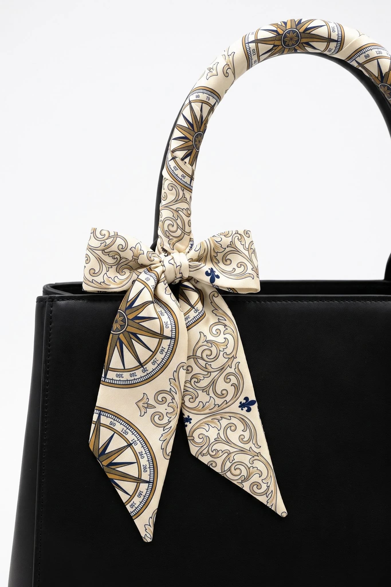 Twilly Rose des vents avvolto e annodato attorno al manico di una borsa in pelle nera