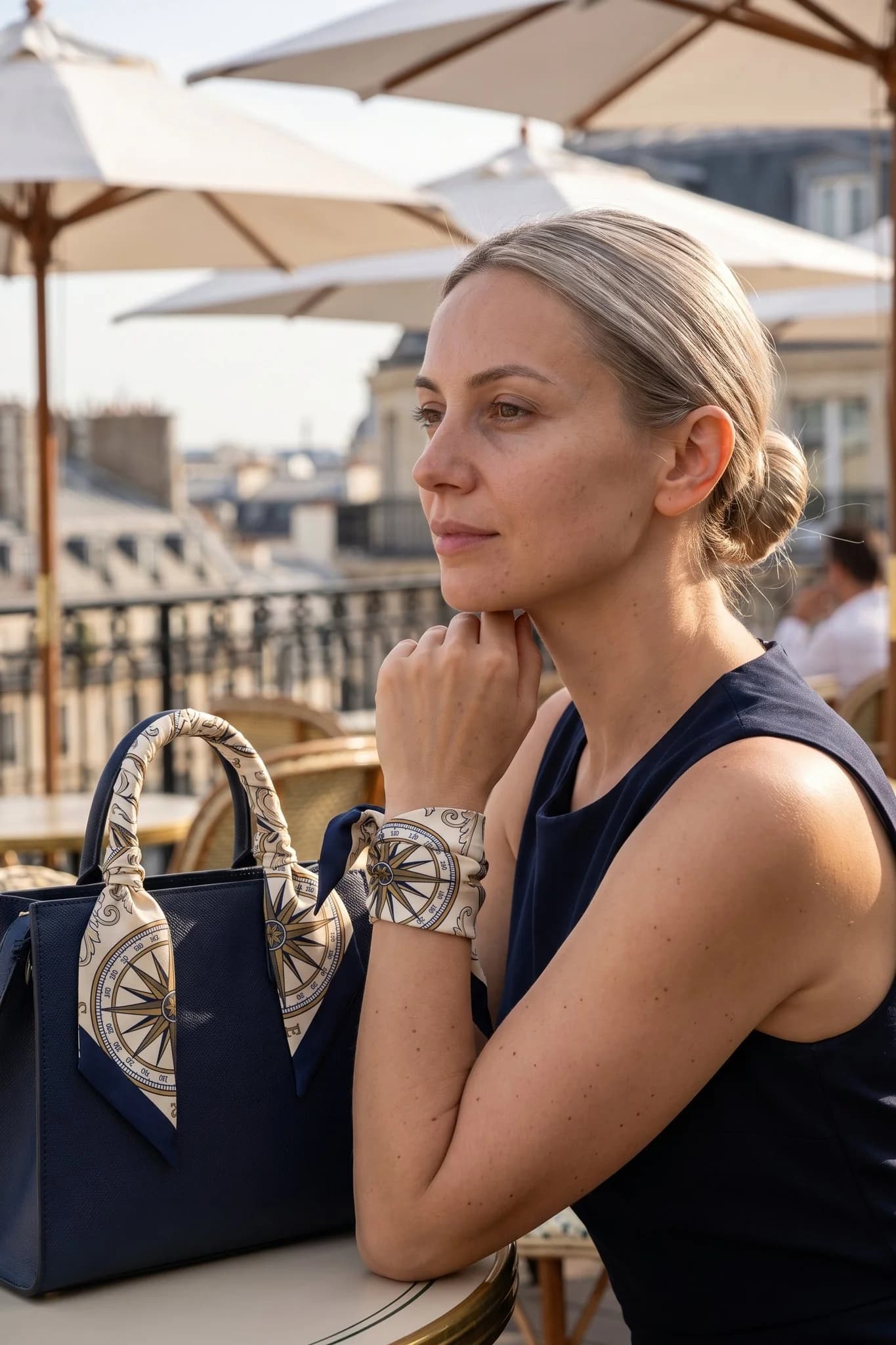 Donna che indossa il twilly Rose des vents al polso e sul manico della sua borsa, terrazza parigina