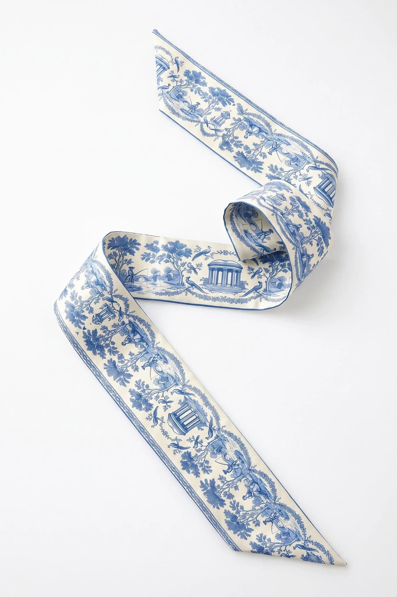 Twilly en soie Toile de rêverie Misciano plié dans la longueur, ruban de soie aux pointes effilées, dessin toile de rêverie sur fond bleu