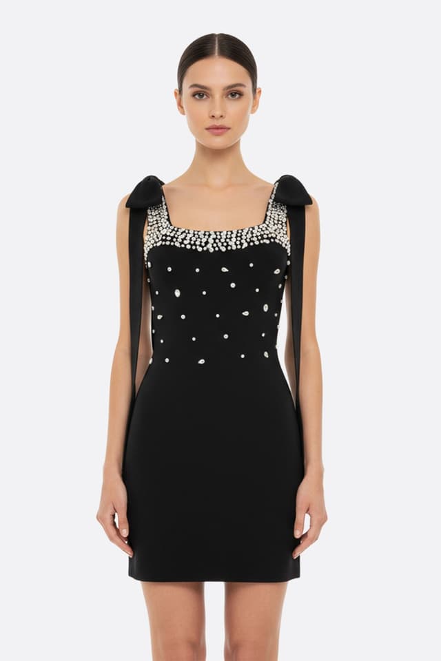 Abito corto nero con inserti di perle e fiocchi raffinati, perfetto per una serata chic e affascinante.
