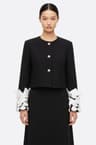 Schwarze Jacke mit Blütenblattärmeln und weißen Federn