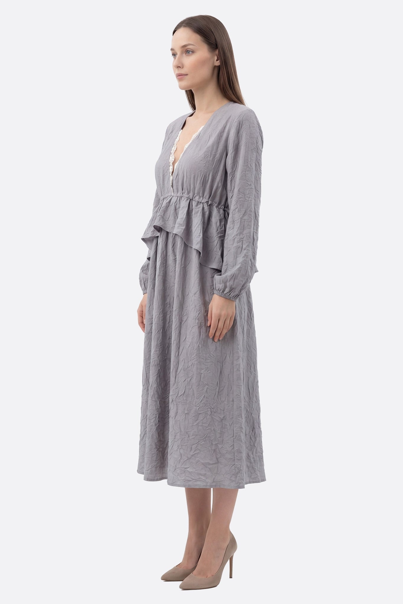 Model im Profil trägt ein graues plissiertes Midikleid mit V-Ausschnitt, Rüschen und verstellbarer Taille