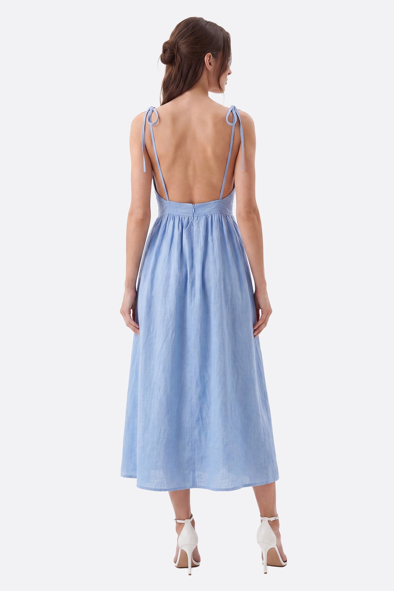 Modella di schiena in abito midi azzurro cielo con schiena scoperta e spalline annodate, tessuto leggero