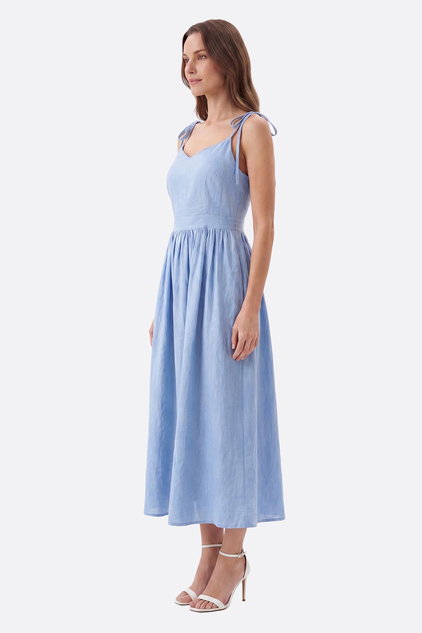 Abito midi azzurro cielo con spalline annodate indossato di profilo da una donna