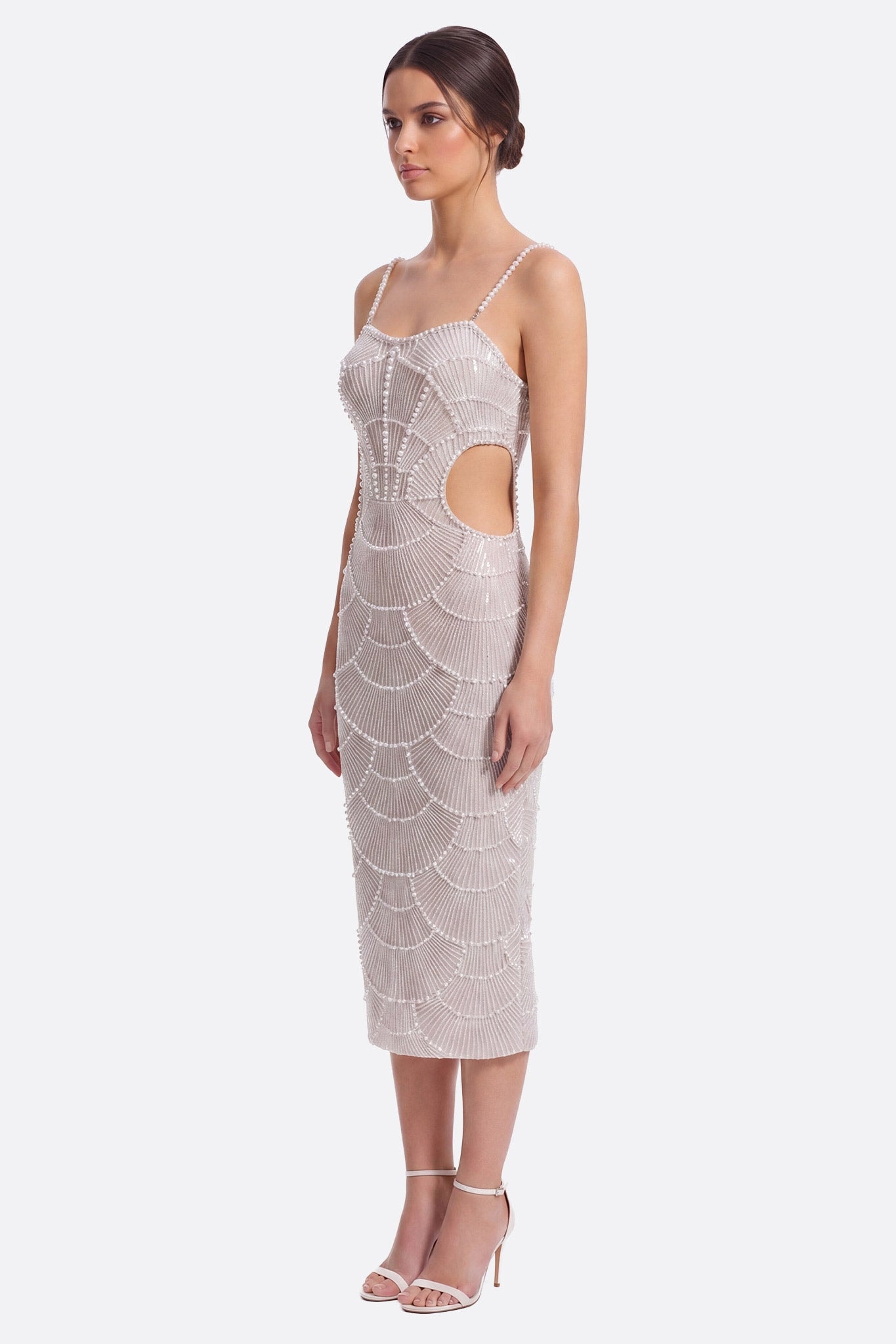 Model side profile wearing a white midi evening dress with pearls and champagne sequins, waist cutout