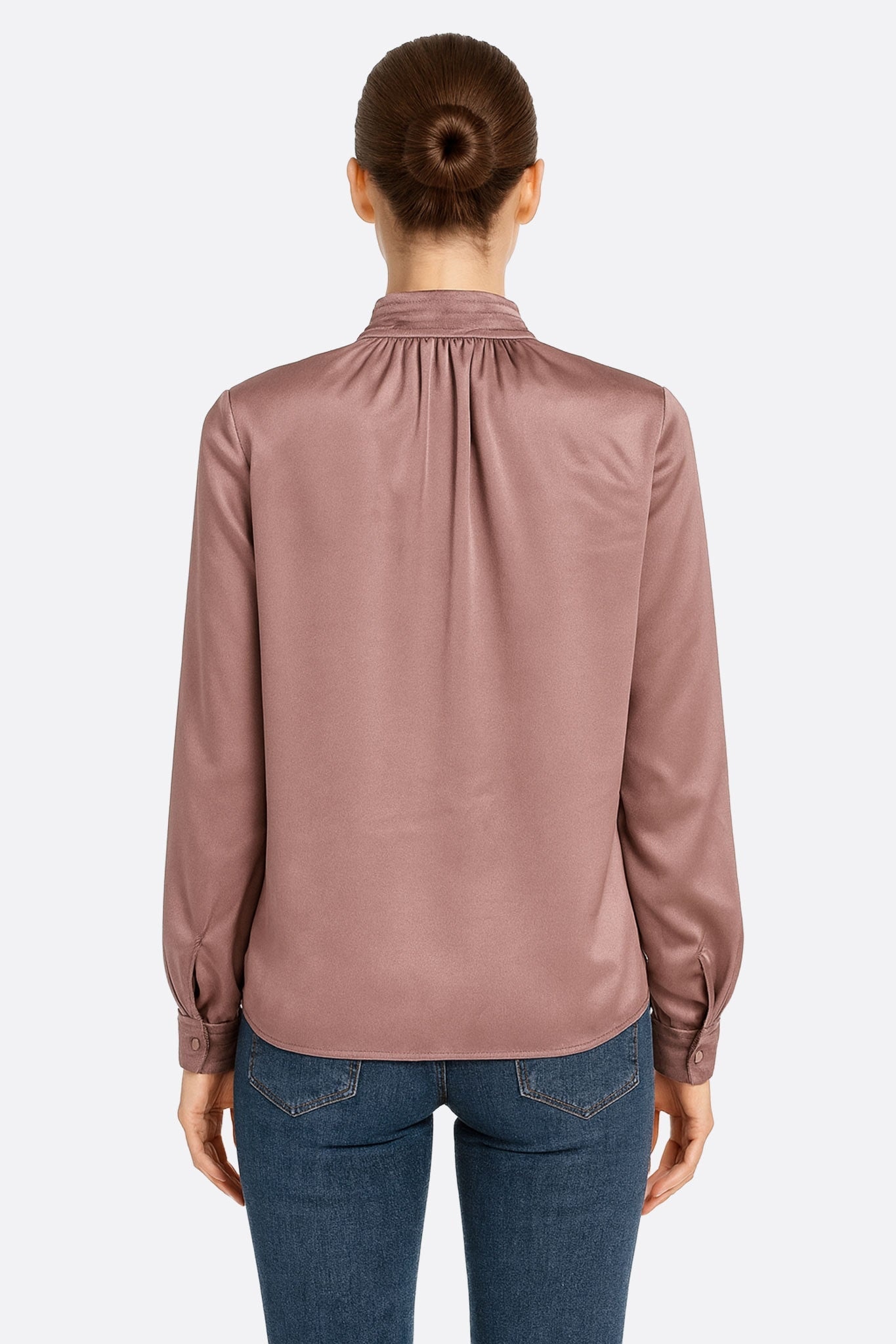 Clean silhouette of the powder pink satin blouse with long sleeves, revealing its delicate stand collar ideal for a...