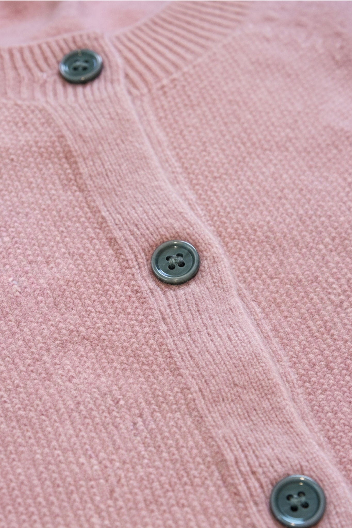 Profilo di un cardigan in lana vergine rosa cipria, che ne accentua le maglie raffinate e la silhouette elegante ideale per...