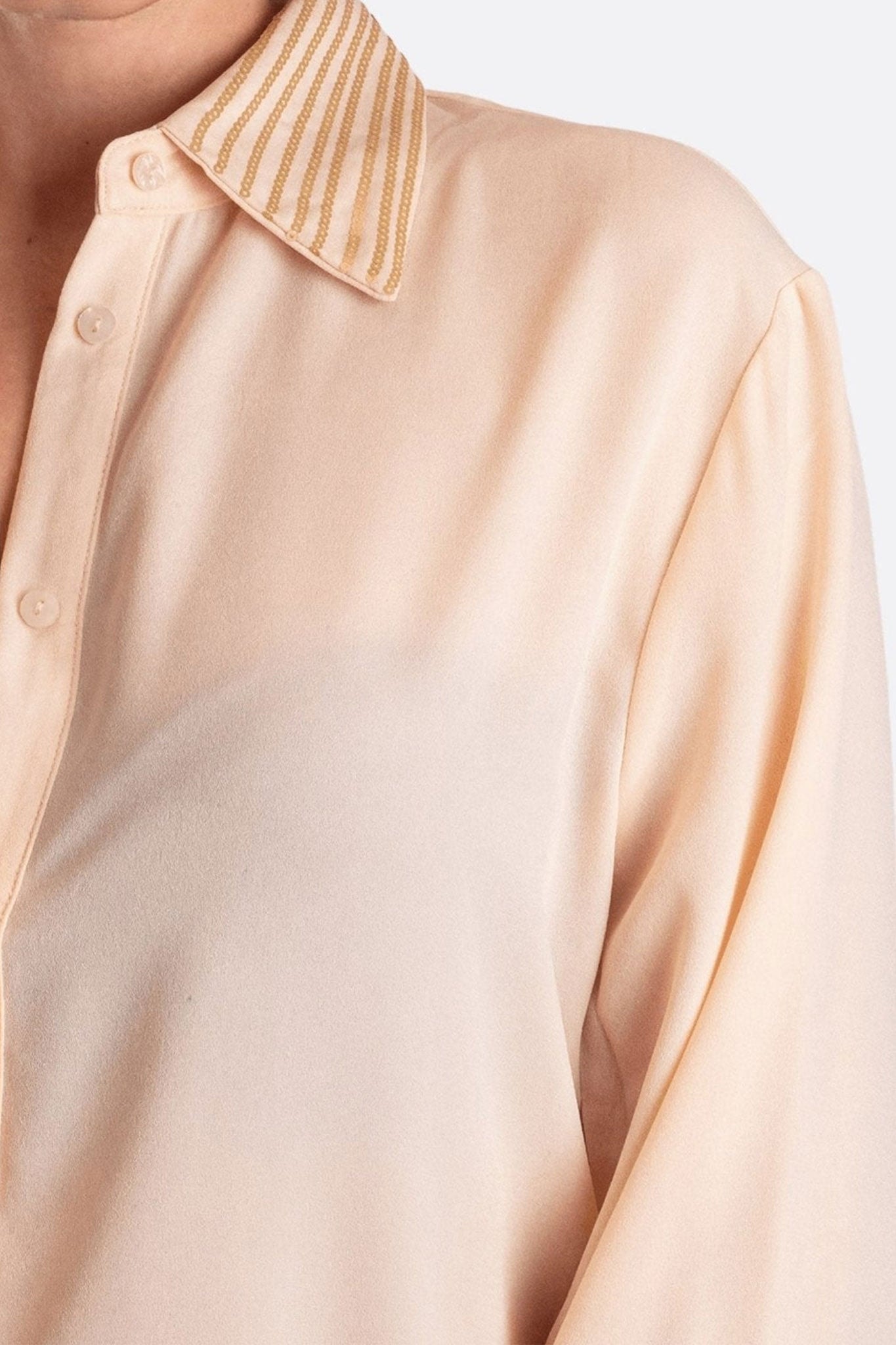 Vista alternativa di una camicia rosa dal colletto classico, evidenziando le paillettes scintillanti per un look sofisticato.