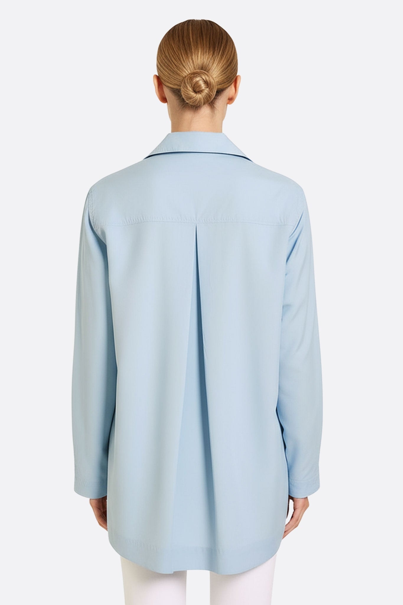Primo piano sulla camicia tunica in cotone azzurro cielo, che evidenzia la fluidità delle maniche lunghe e la sua discreta eleganza.
