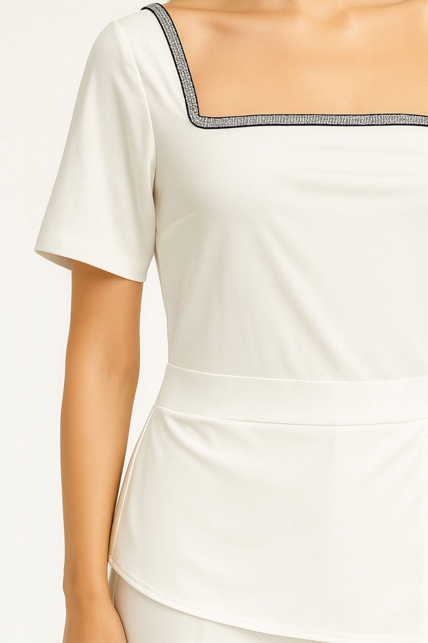 Back detail of the white asymmetric jumpsuit, showcasing its luxurious texture and an elegant contrasting accent