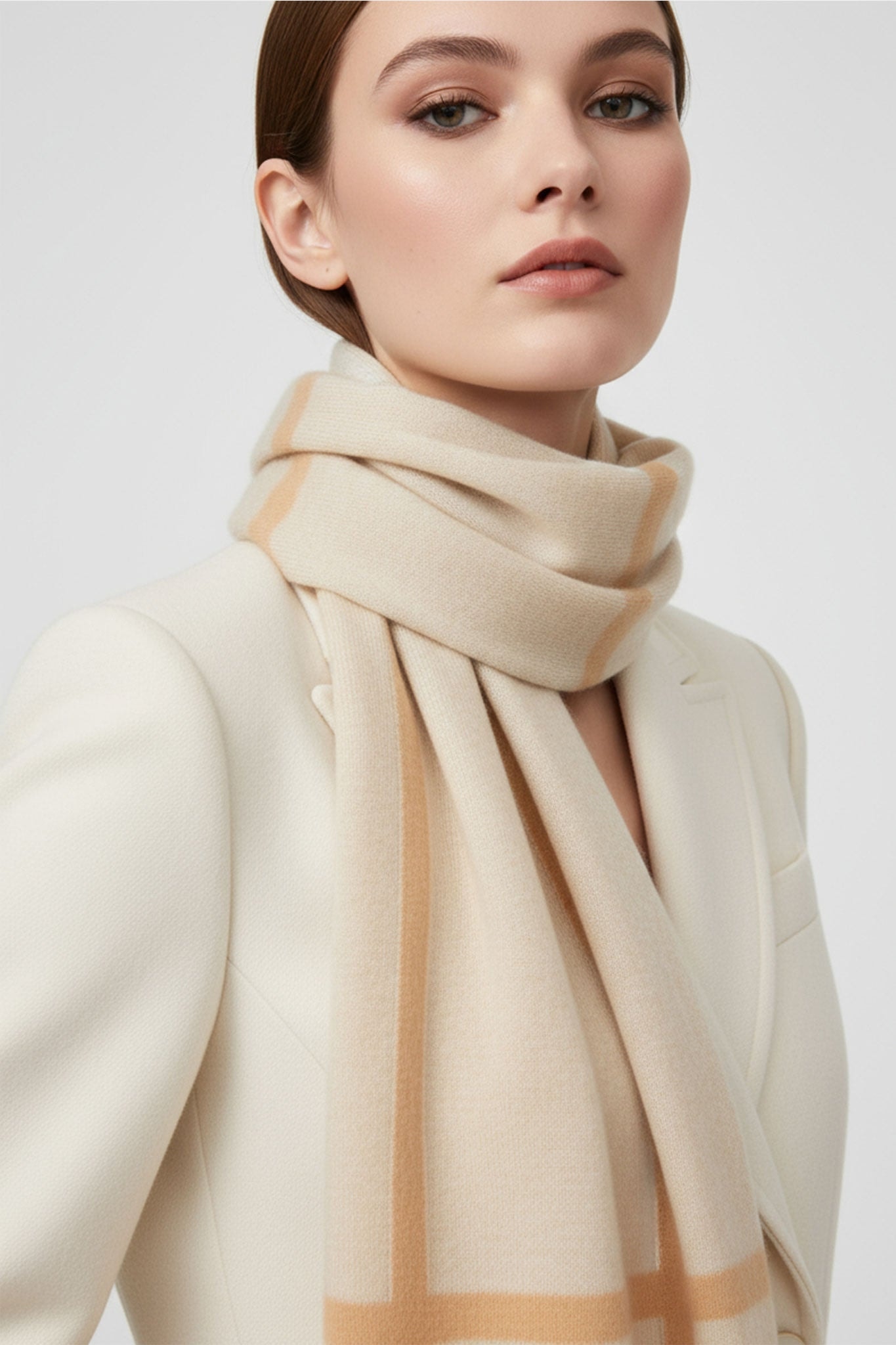 Close-up on the brown striped pattern of a beige cashmere scarf, chic accessory for cool winter days.