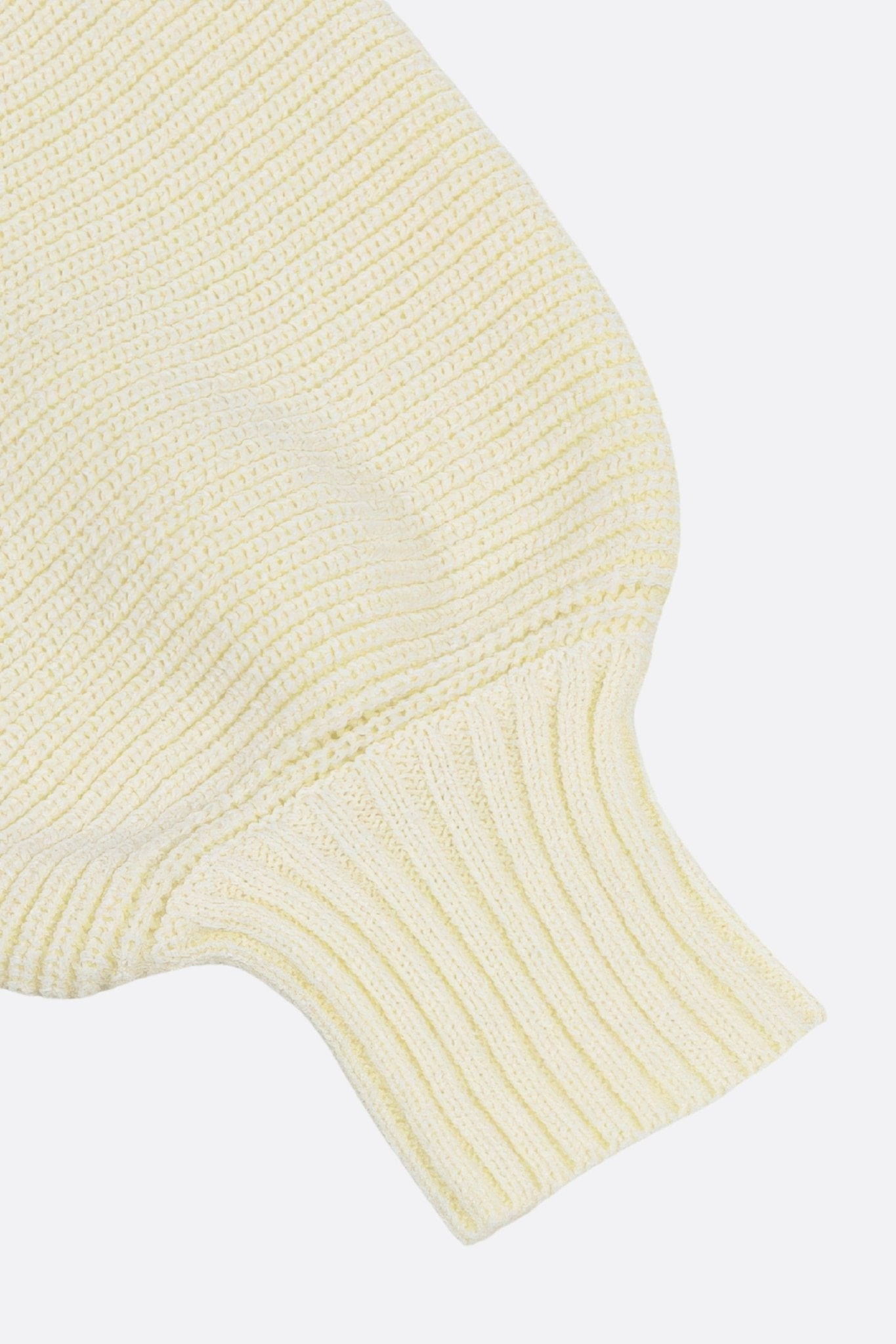 Hintergrund in ecru-weißer Strickware, der die weiche und raffinierte Textur dieses eleganten Sets für den Alltagsstil offenbart.