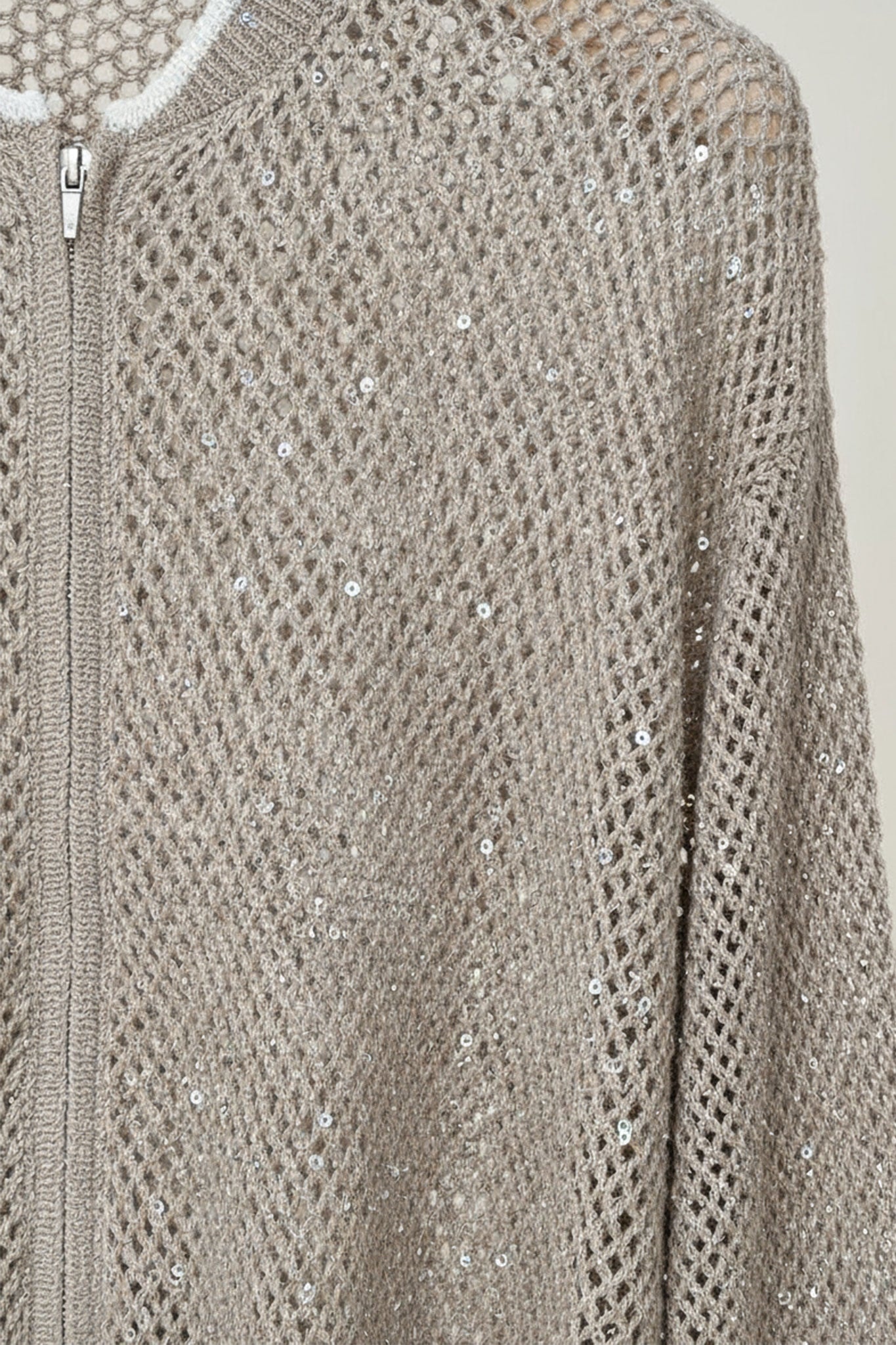 Detalle del chaleco beige arena con cremallera de algodón y tencel, calado y realzado con lentejuelas, perfecto para un look elegante en...