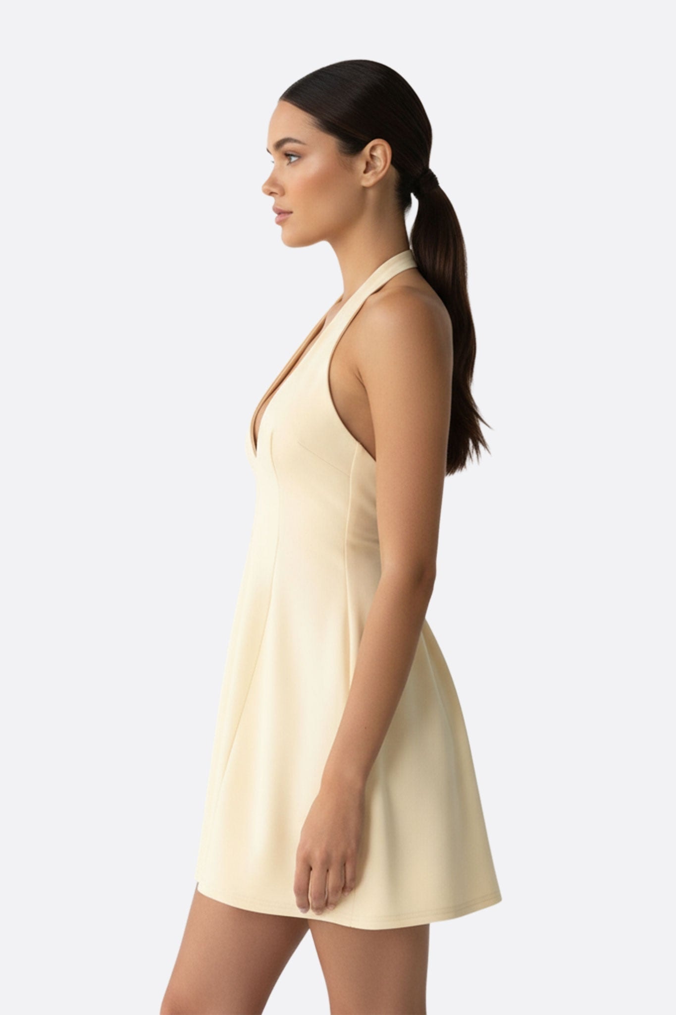 Zoom sur le décolleté profond d'une robe courte beige évasée, idéale pour sublimer une silhouette élégante.