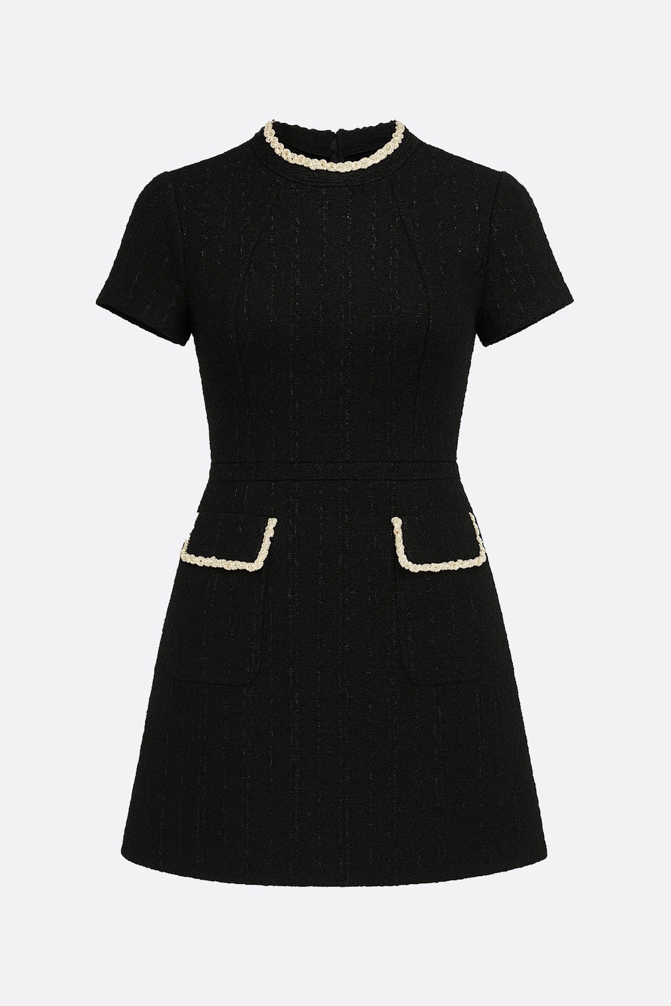 Zoom sur le col bijou doré de la robe courte en tweed noir, ajoutant une touche d'élégance à votre tenue chic.