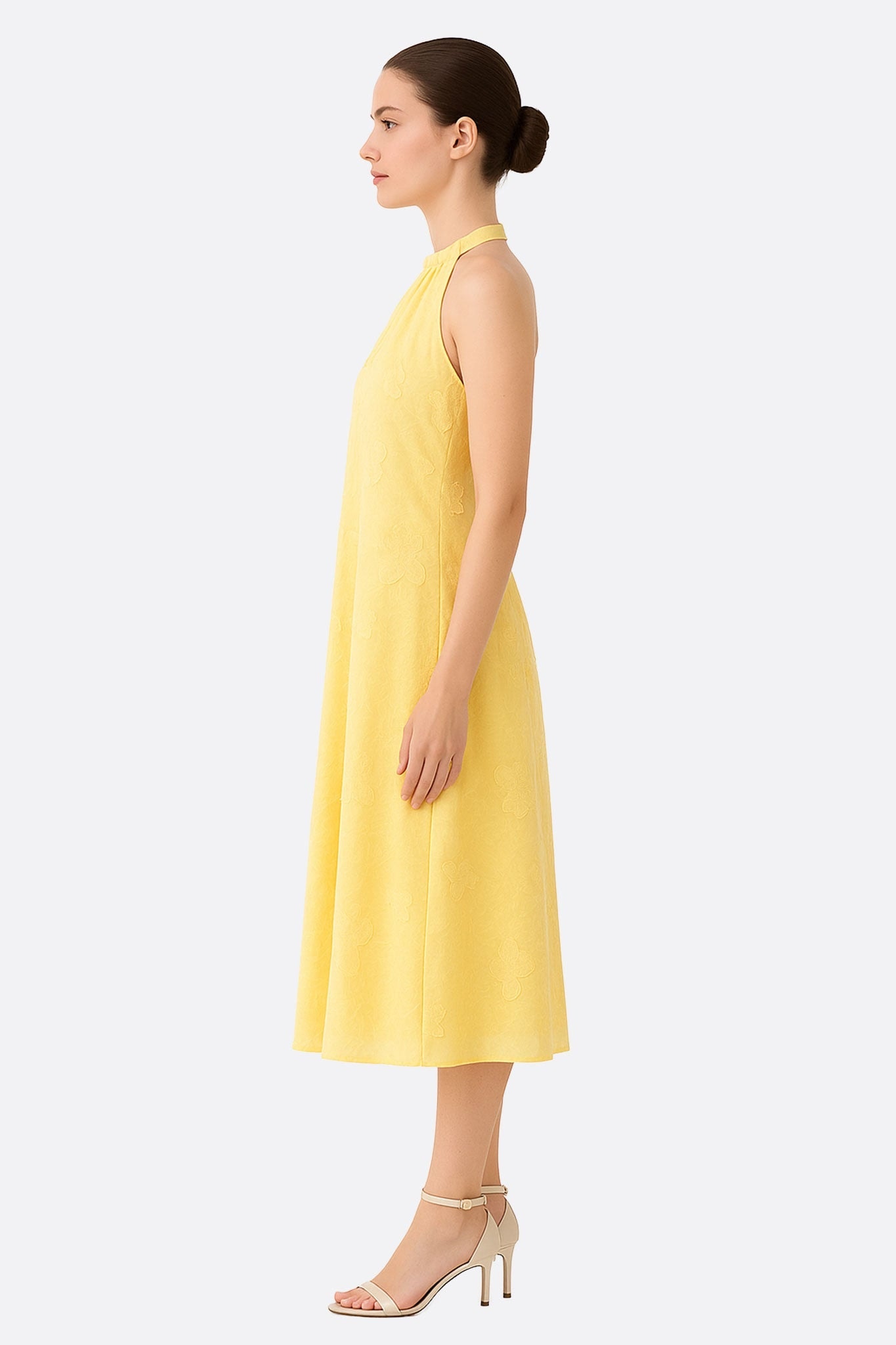 Détail élégant de la robe jaune en jacquard fleuri, mettant en avant son col haut et son tissu délicat, parfait pour les...