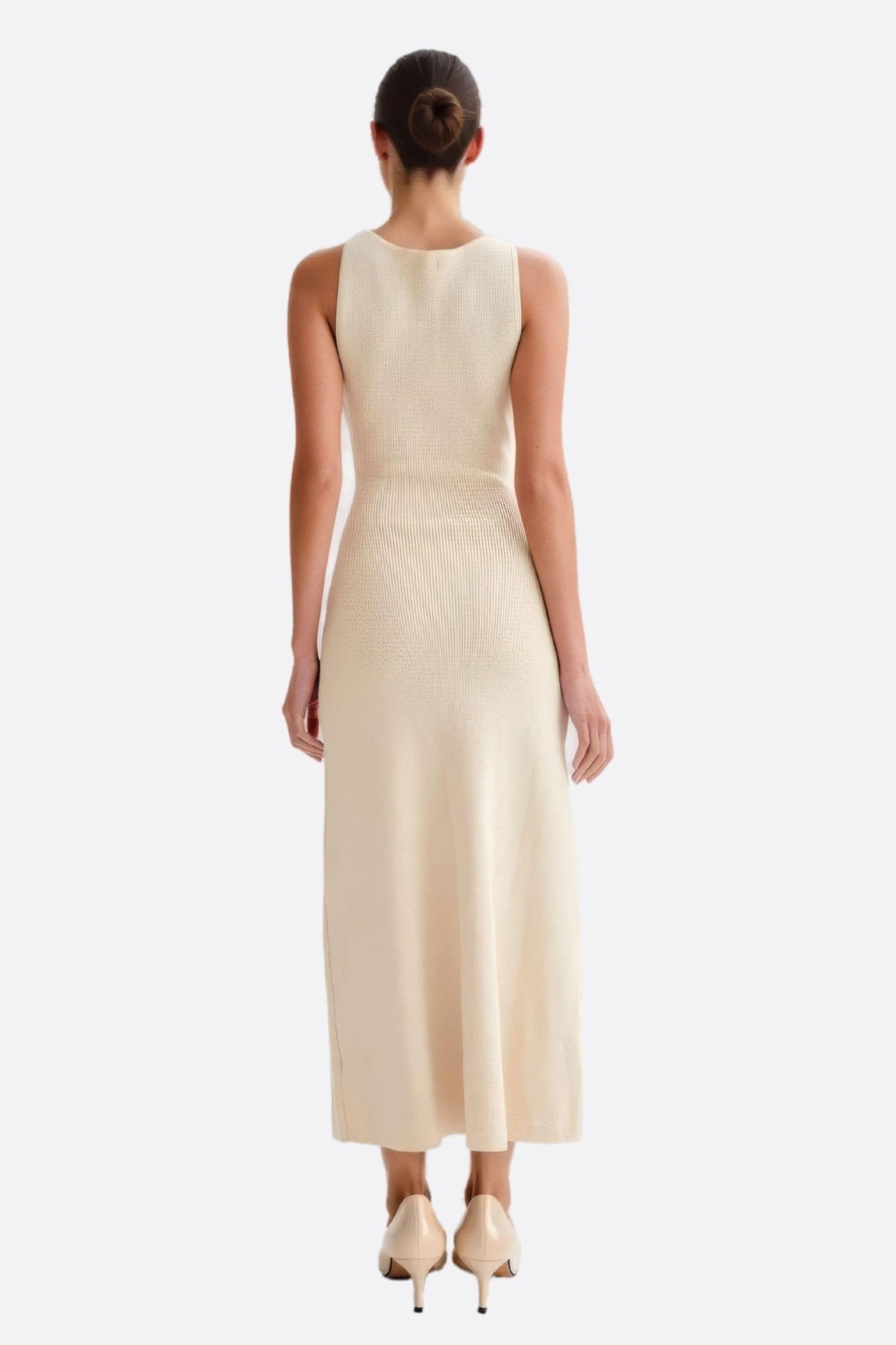 Vestido blanco acanalado sin mangas, vista 3/4, resaltando el corte moderno y la textura refinada, ideal para el...