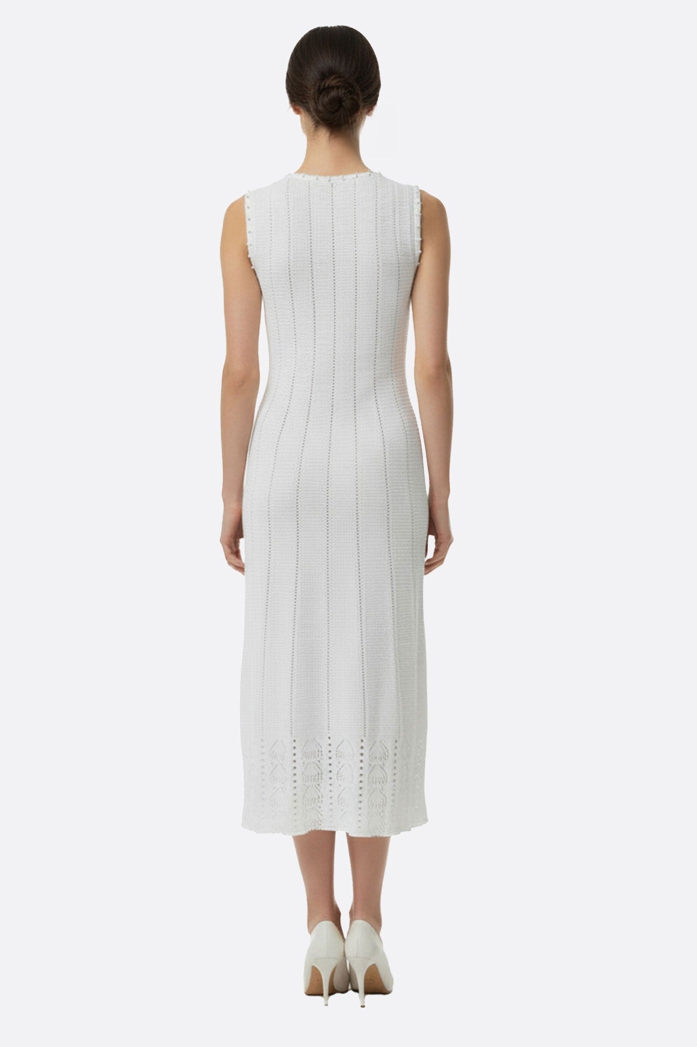 Angle différent de la robe longue blanche sans manches, en maille perlée, illustrant sa légèreté parfaite pour les...