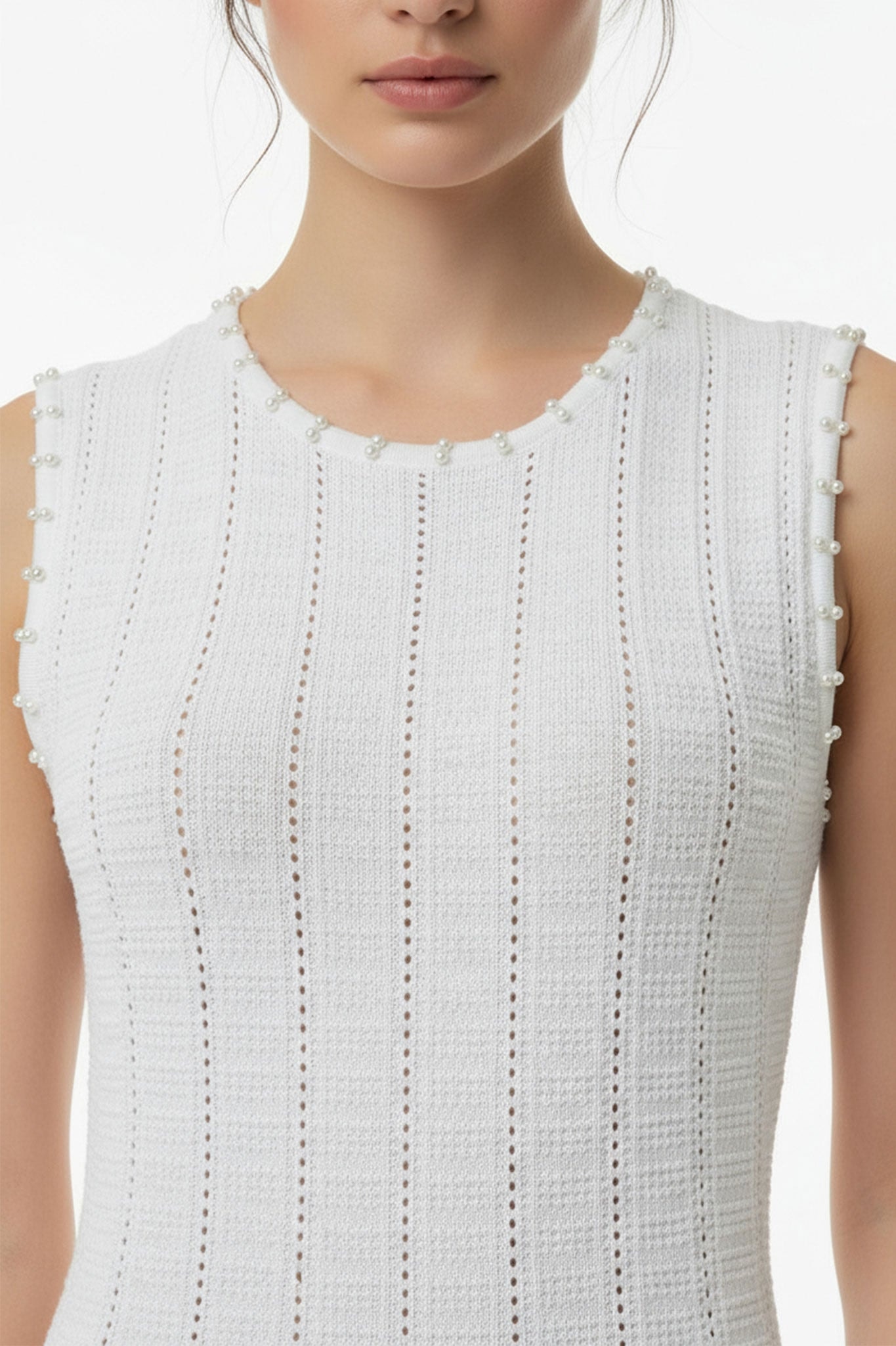 Détail en angle de la robe longue blanche en maille perlée, idéale pour des événements estivaux raffinés et élégants.