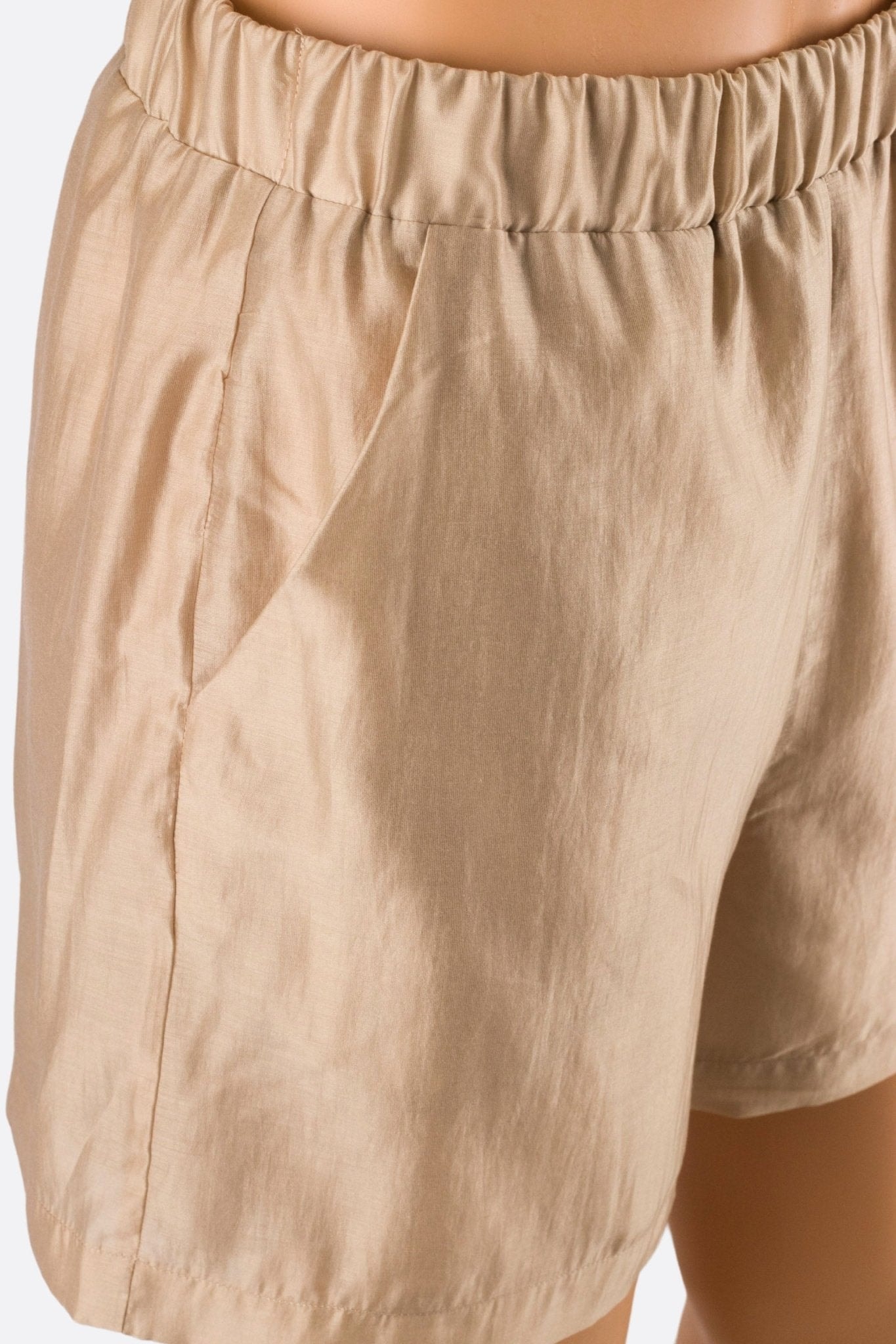 Nahaufnahme der leichten beigen Shorts mit elastischem Bund, ideal für einen eleganten Look an sonnigen Tagen.