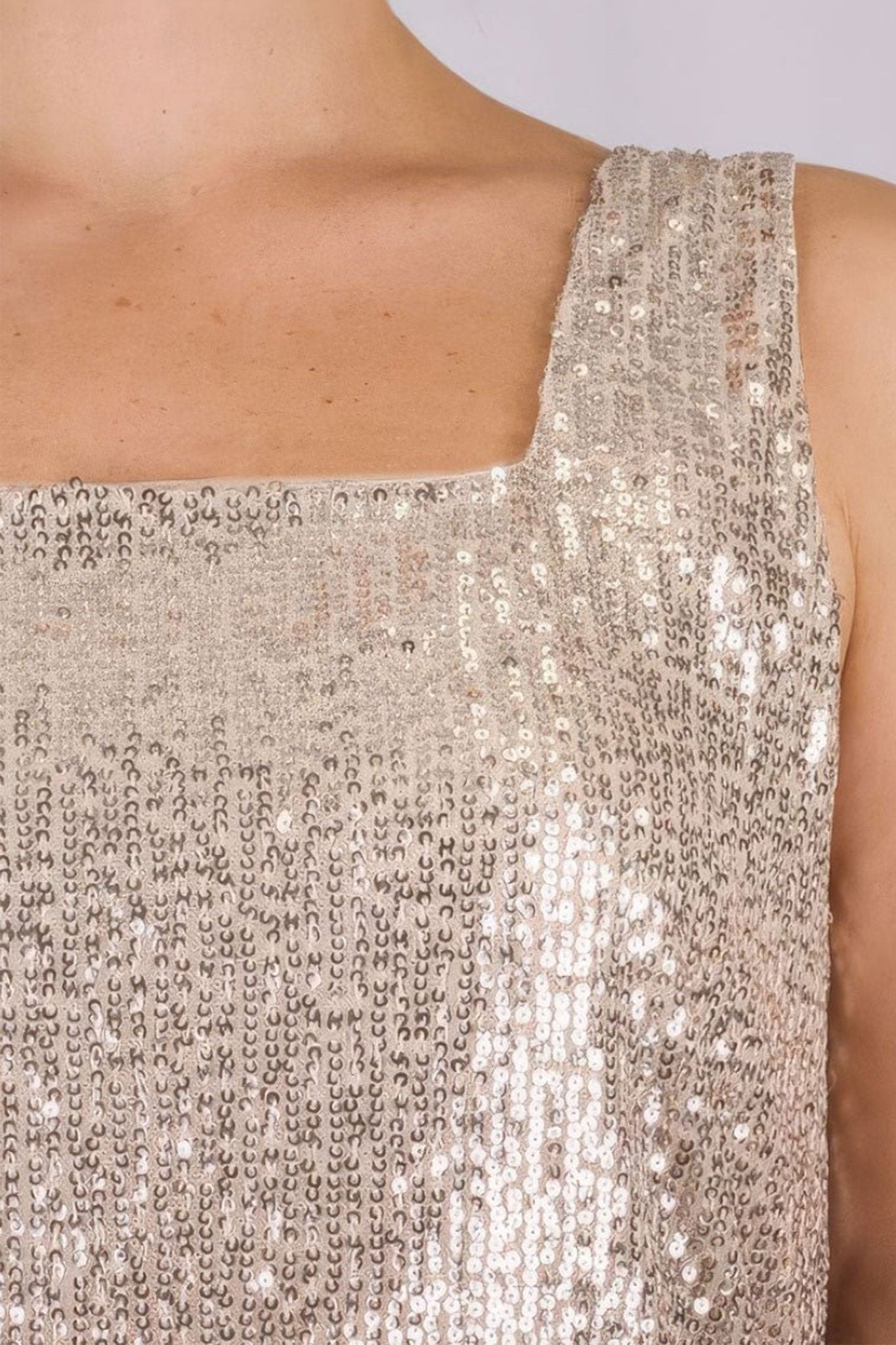 Detail des beigen Tops mit schillernden Sequins, das seine fließende Textur und seinen eleganten Charme für glamouröse Abende hervorhebt.