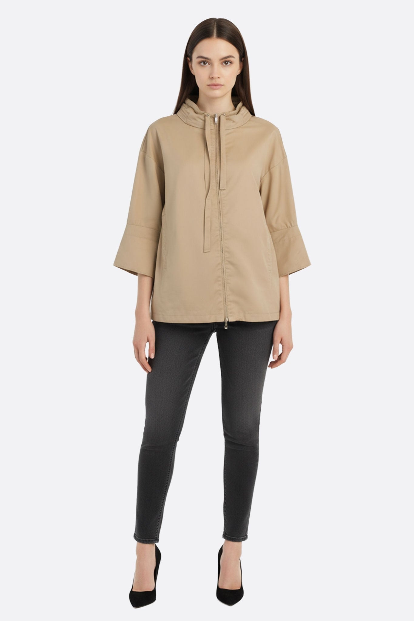 Détail rapproché de la veste beige ample avec capuche intégrée, idéale pour une tenue raffinée lors des soirées.